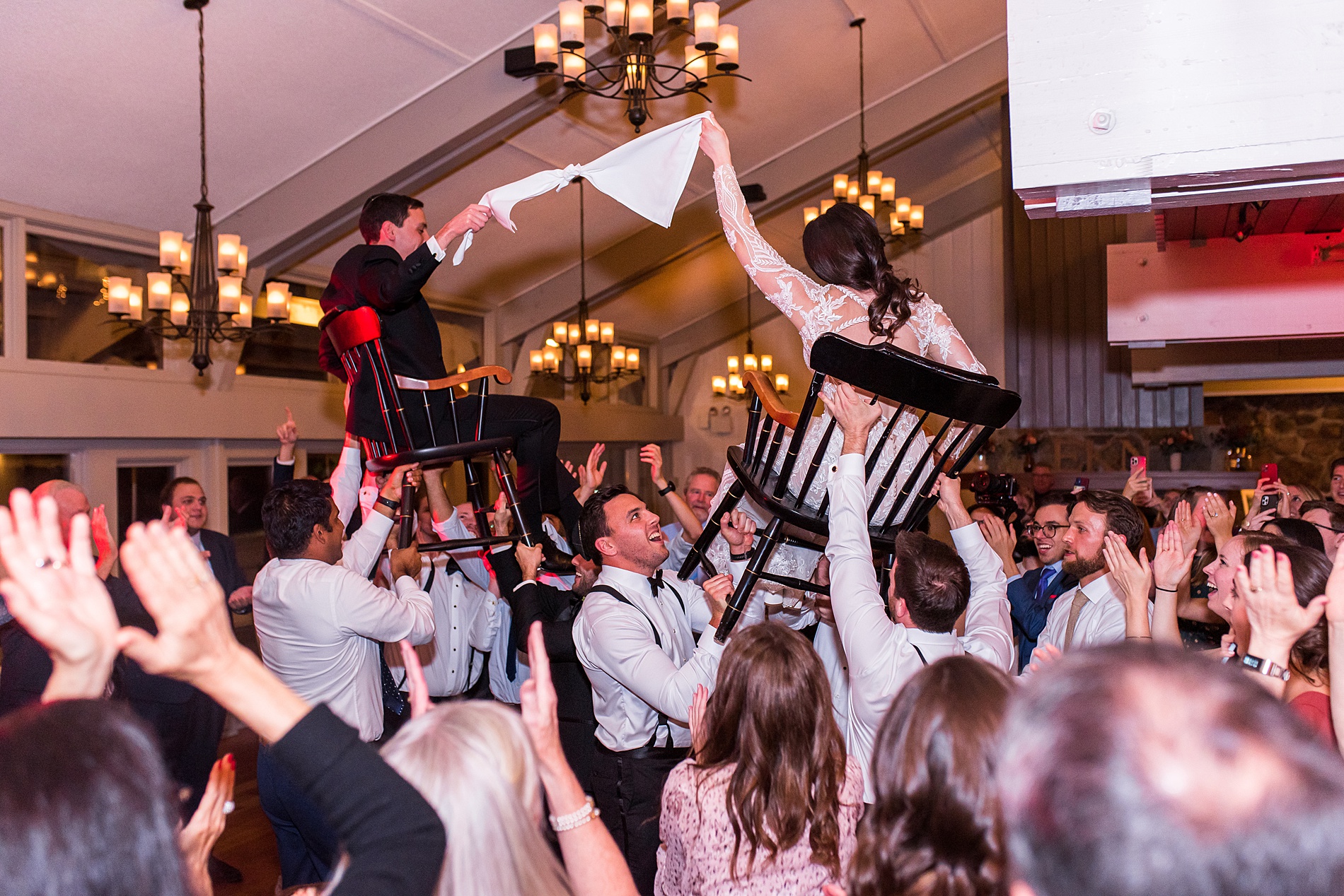newlyweds raised on chairs during Jewish tradition celebrating their union