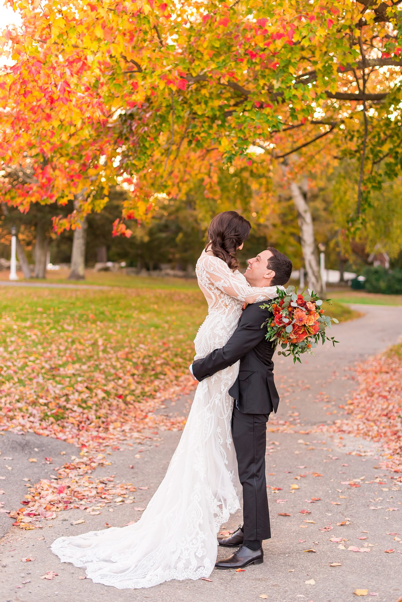 groom lifts bride up for a kiss at MA fall wedding