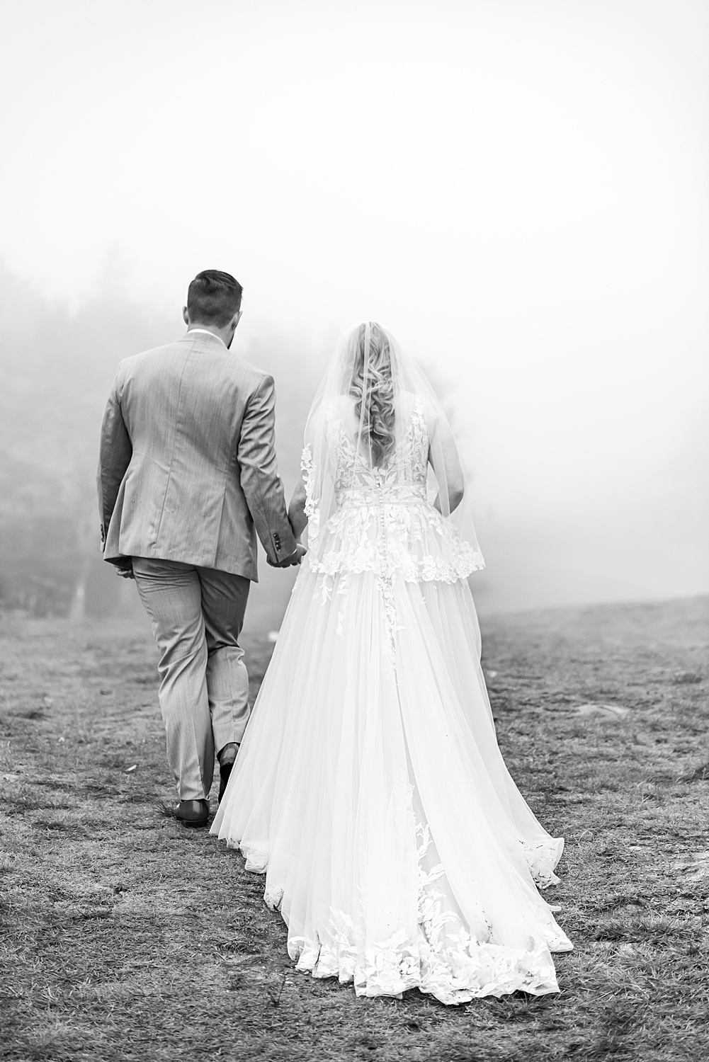 bride and groom at the summit of mountain surrounded by thick fog