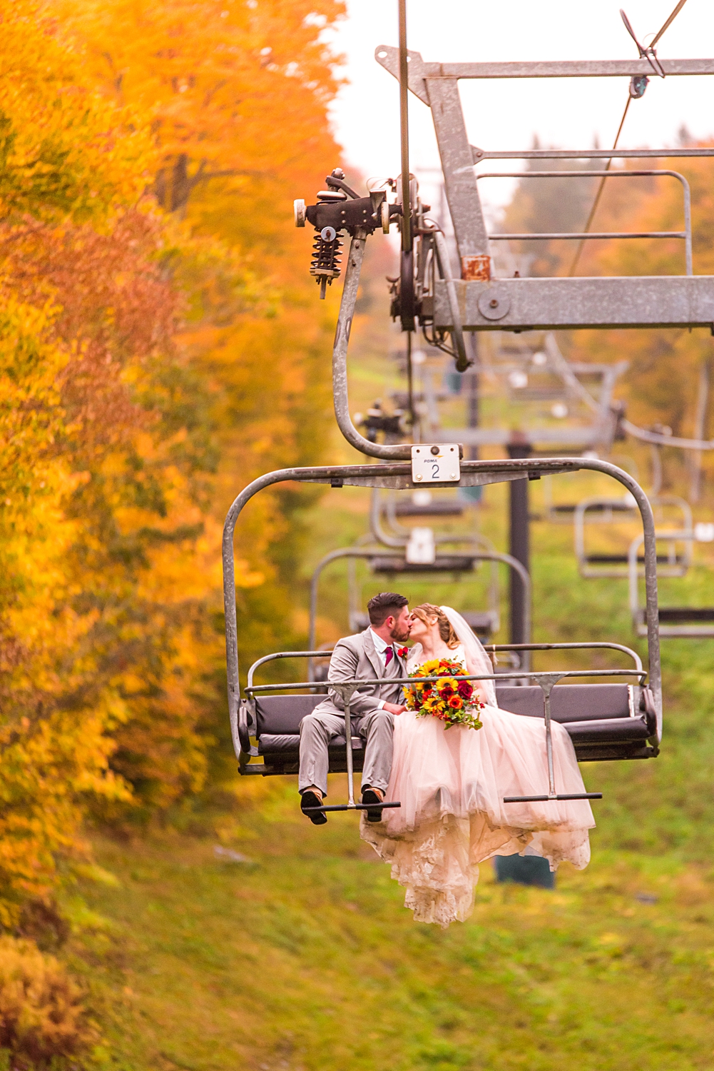 couple descending from the mountain top in a ski lift at Mount Sunapee Resort Wedding in New Hampshire