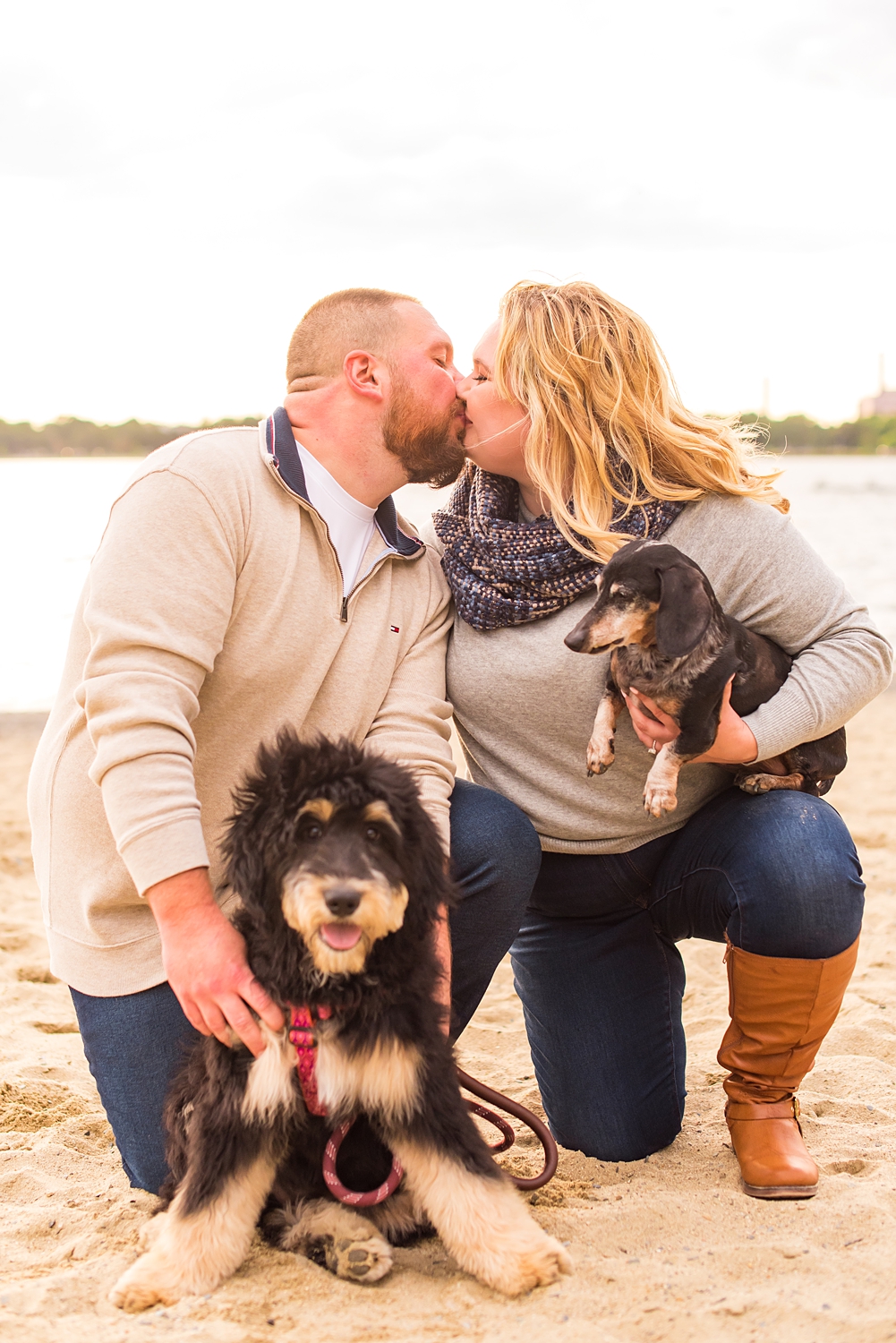 couple holds their dogs as they kiss