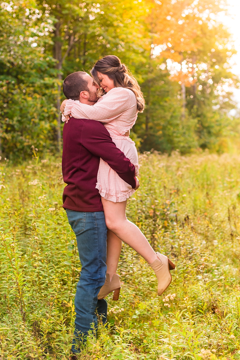man lifts up his fiance during NH engagement session