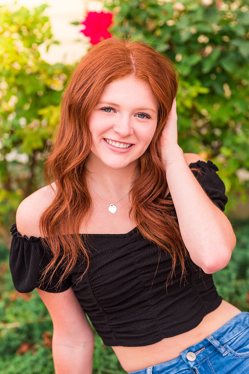 girl in black top poses for senior portraits in New Hampshire
