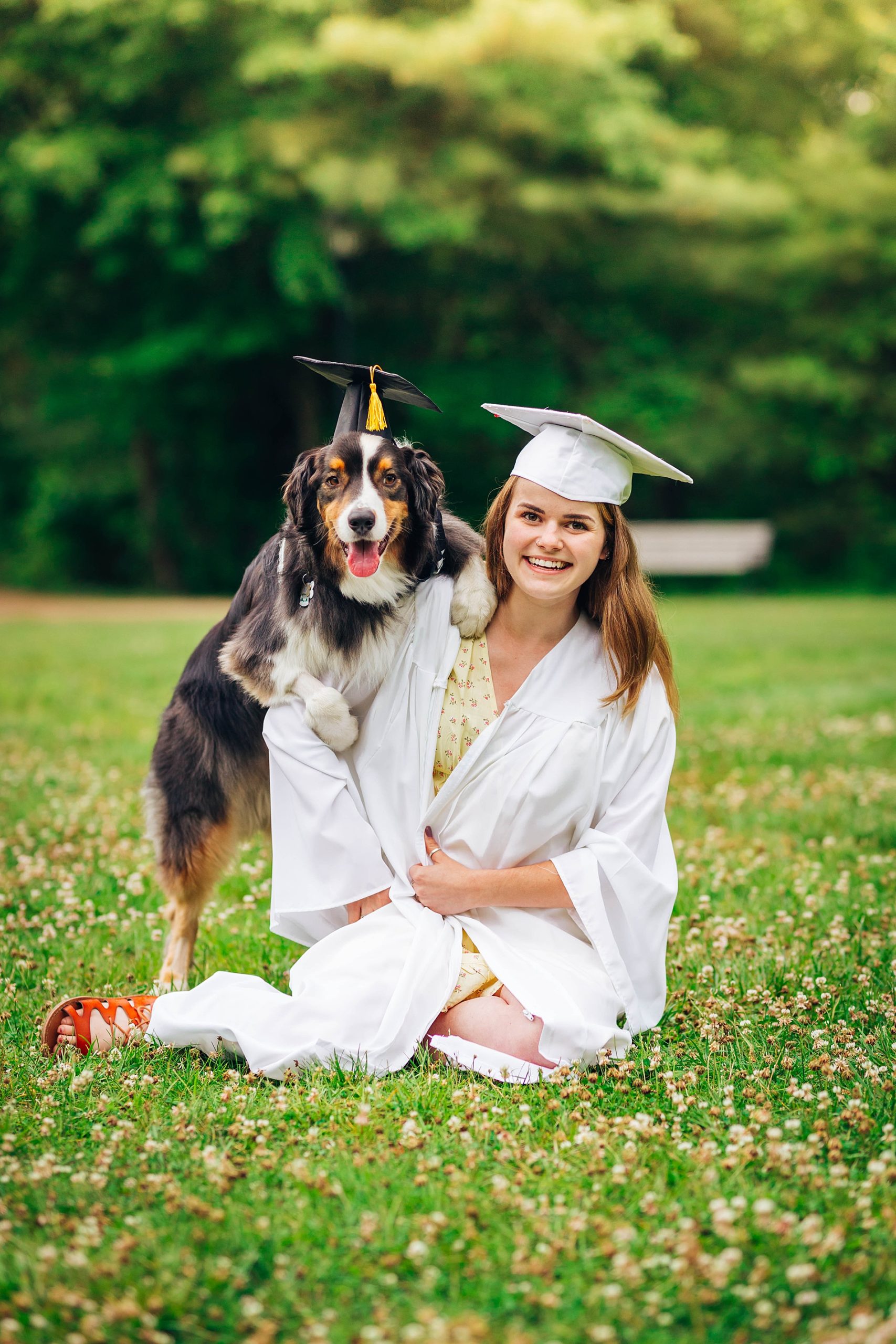 graduate in white cap and gown with her dog 