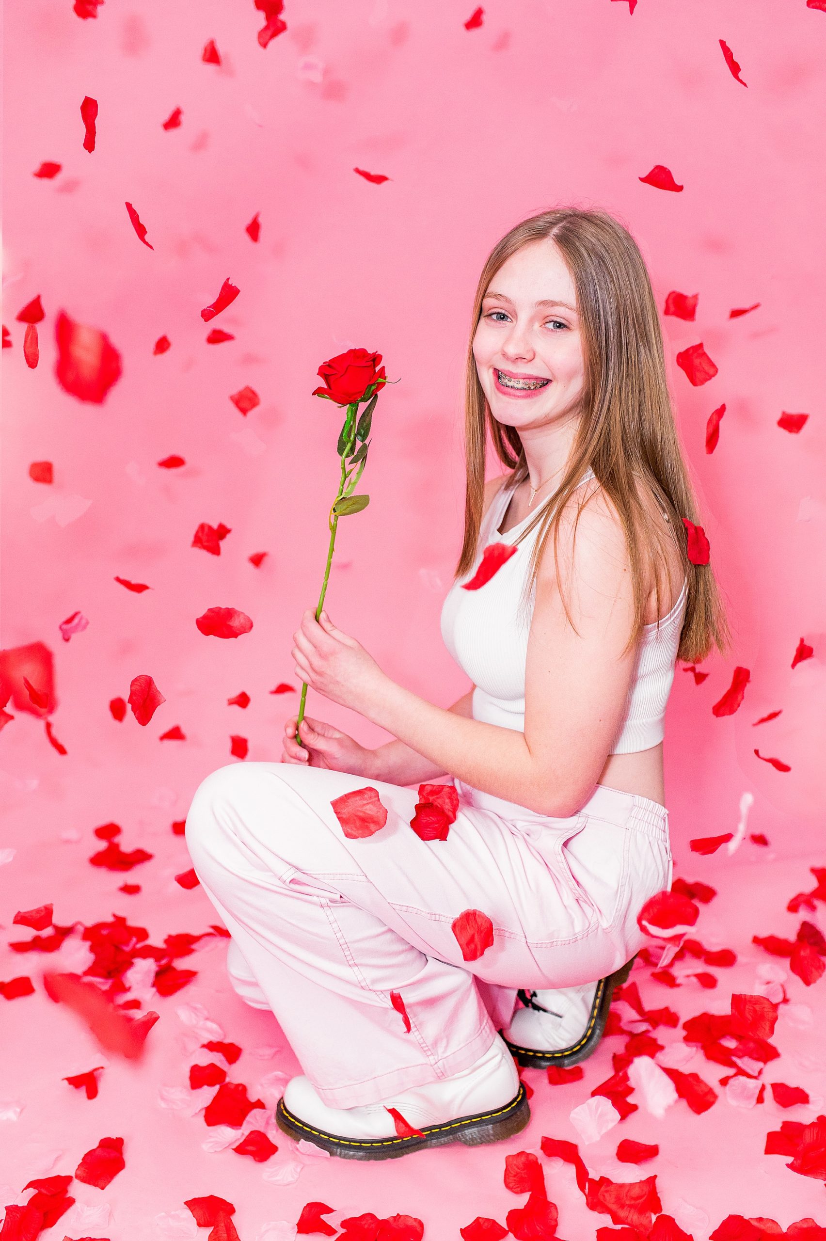 senior girl poses with red rose