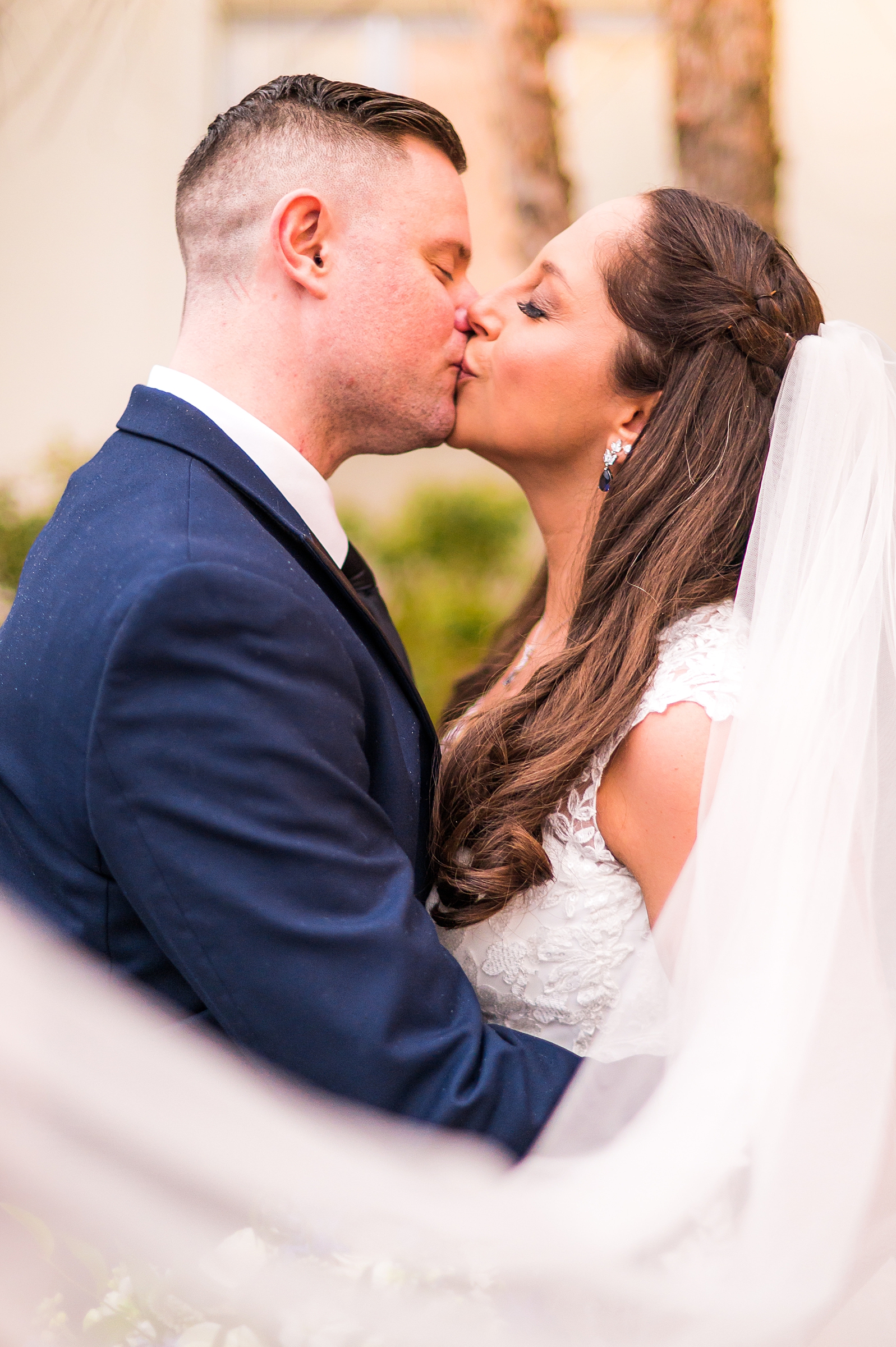 bride and groom kiss as veil swirls around them