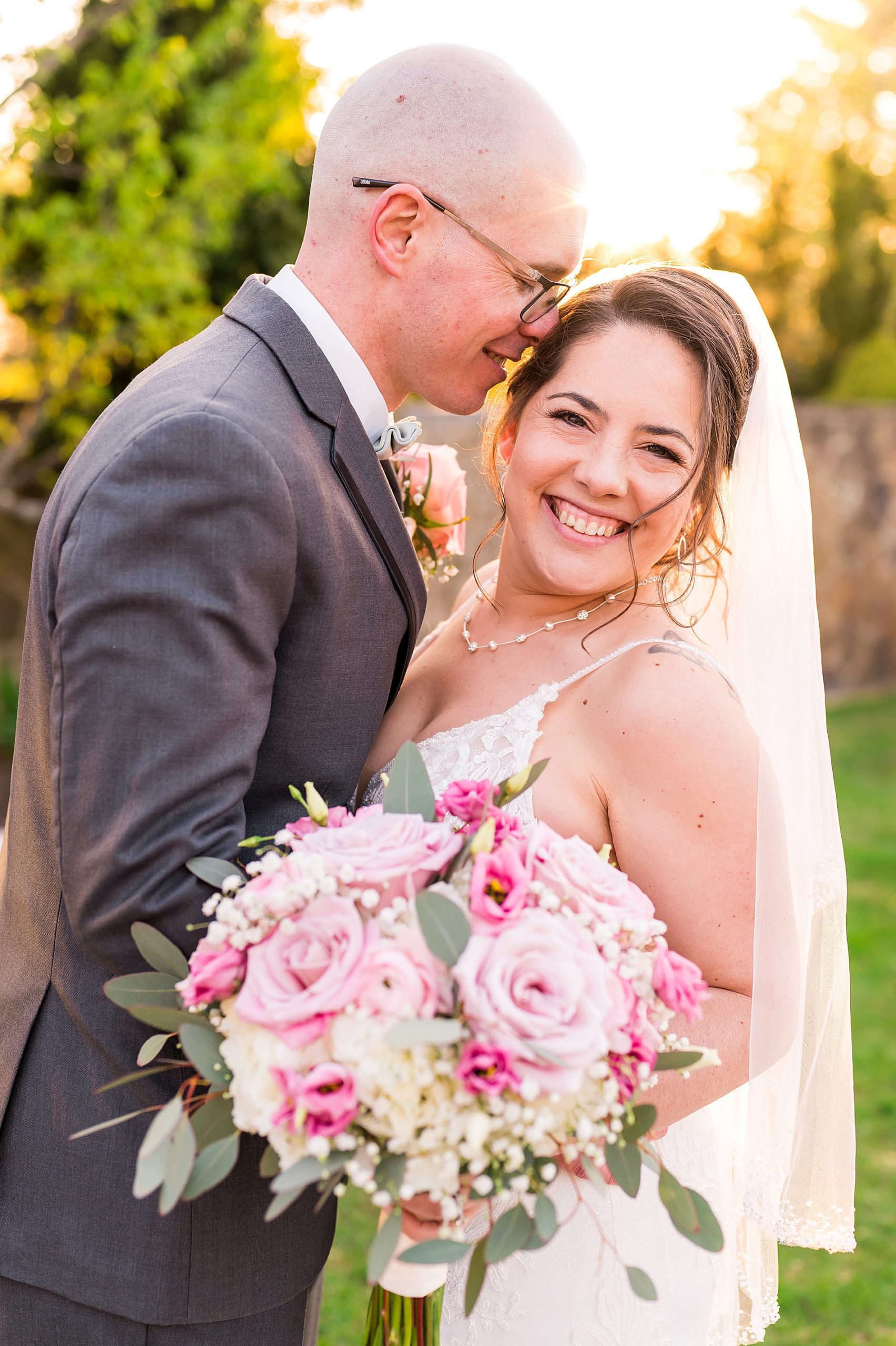 newlyweds hug while bride holds pink flower bouquet