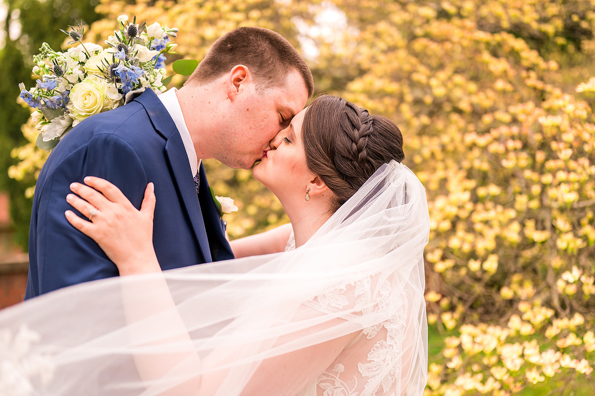 couple kiss as bride's veil wraps around them