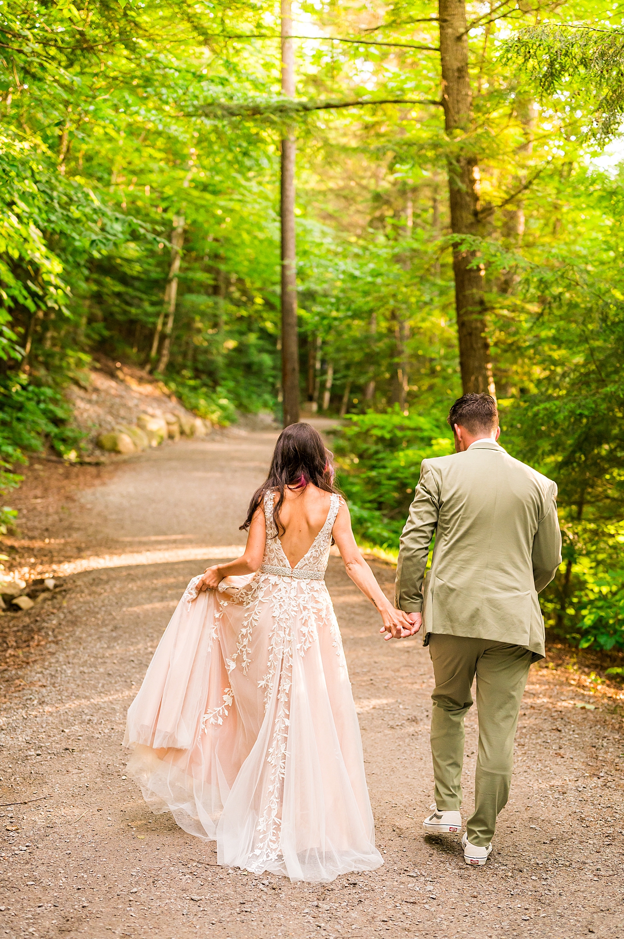 couple hold hands and walk together down a trail