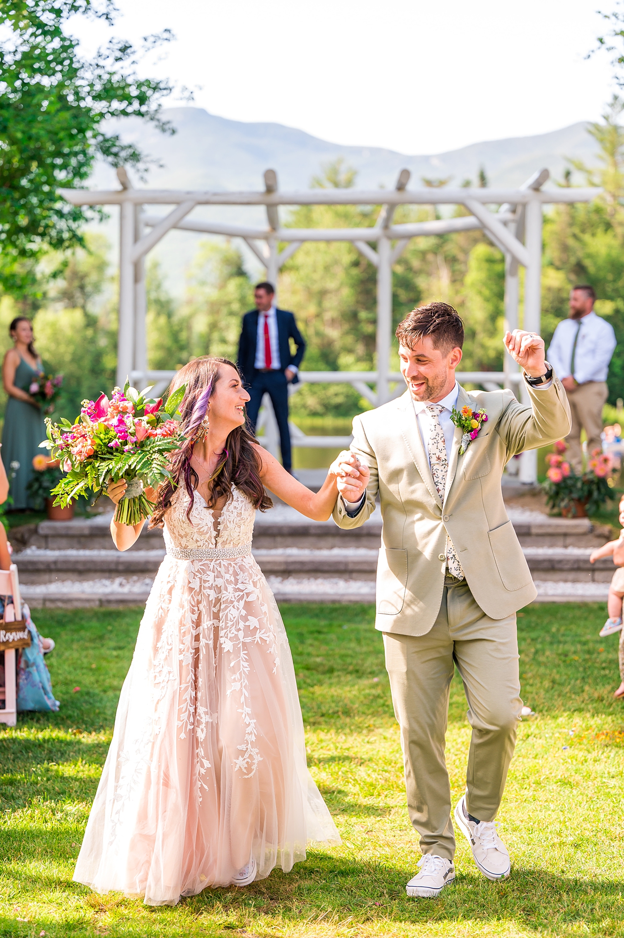 newlyweds walk together as husband and wife after bright + Colorful summer wedding ceremony