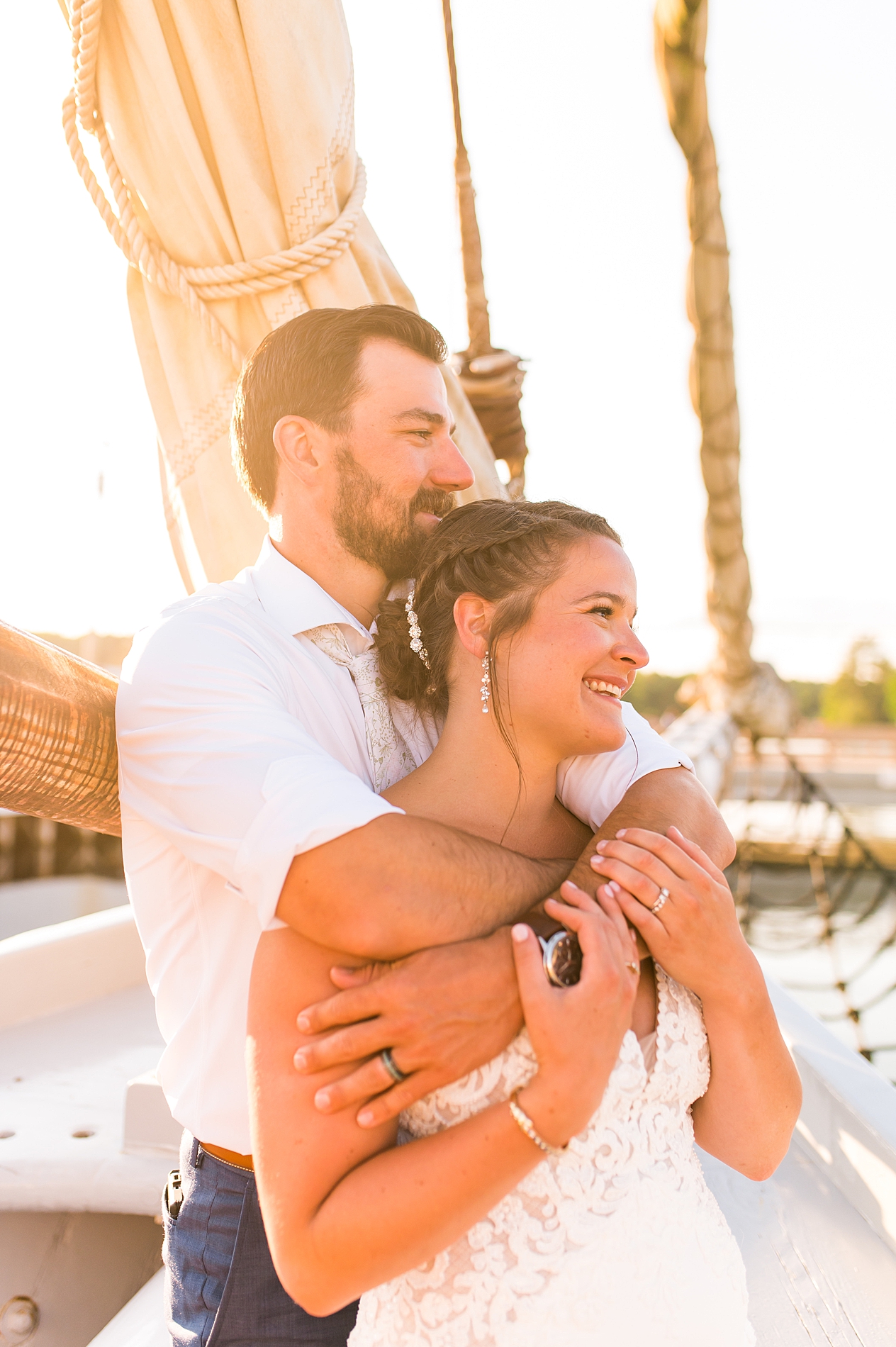 groom hugs bride in candid photo on sailboat 