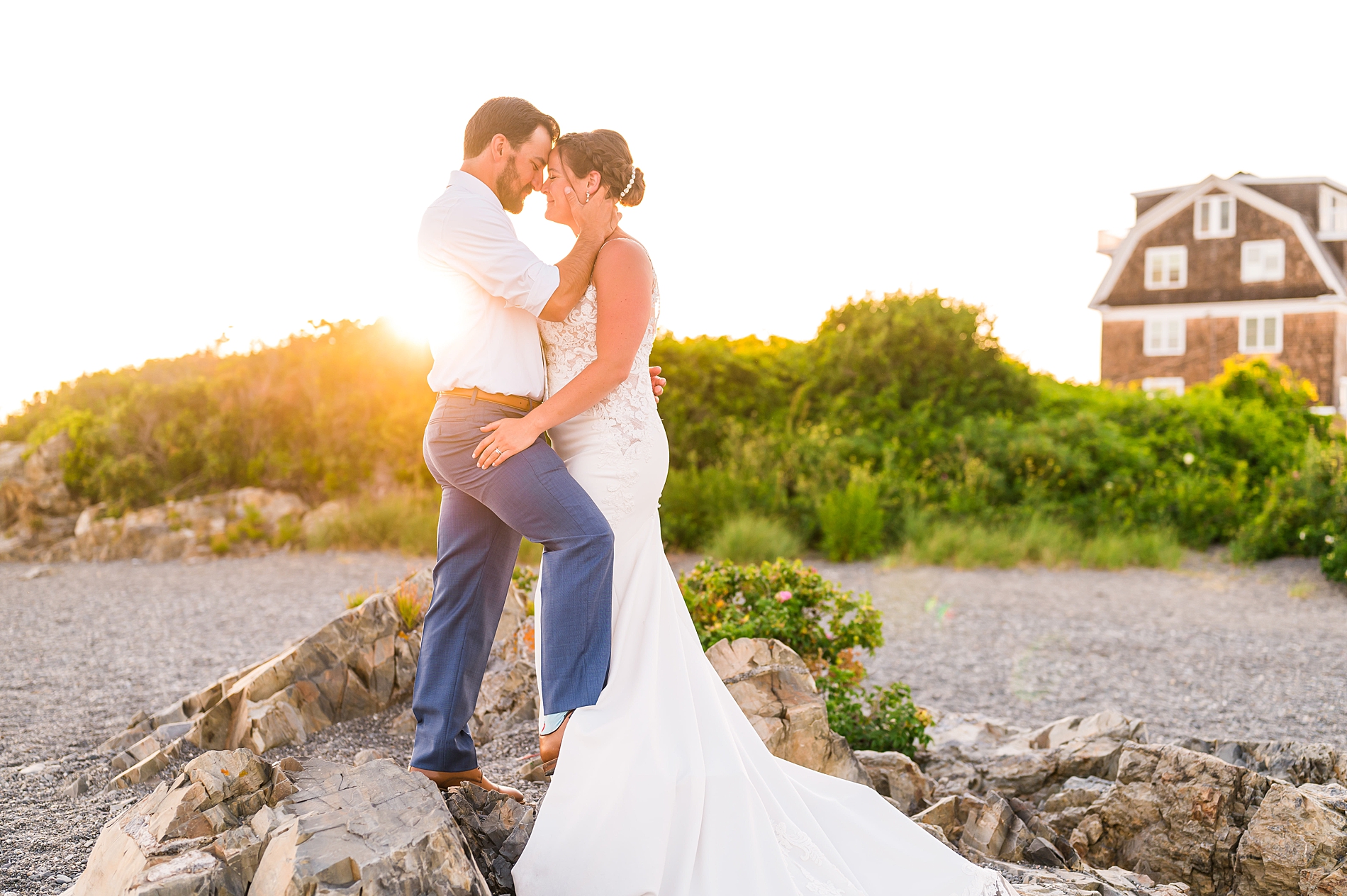 bride and groom stand on rocks at beach in Maine