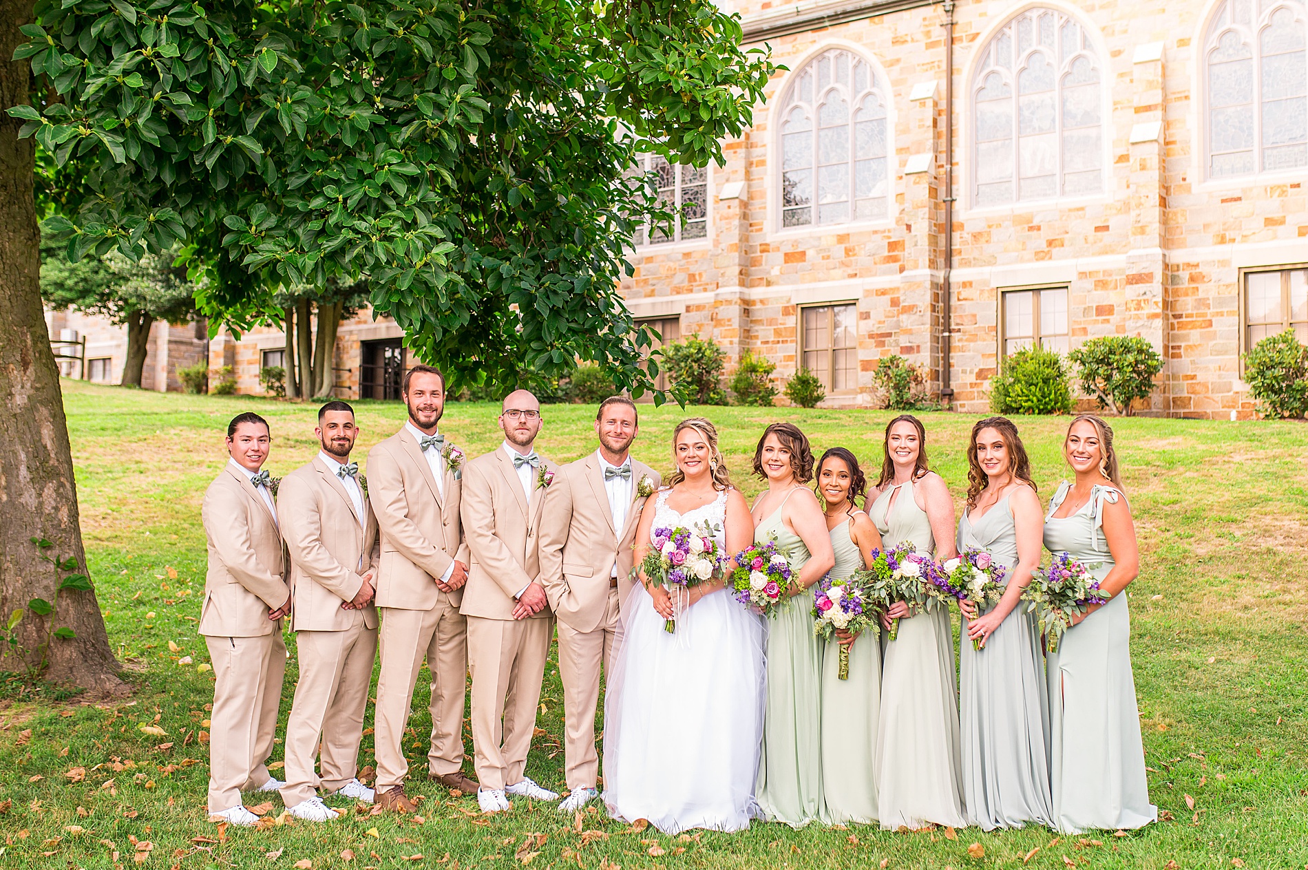 bridal party surrounds bride and groom after wedding ceremony