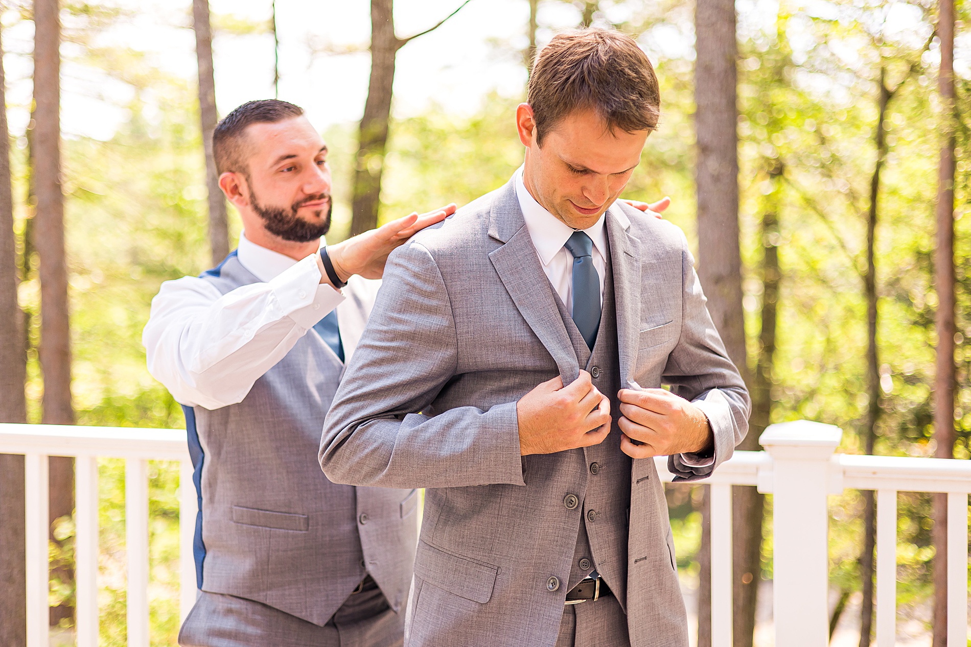best man helps groom with jacket