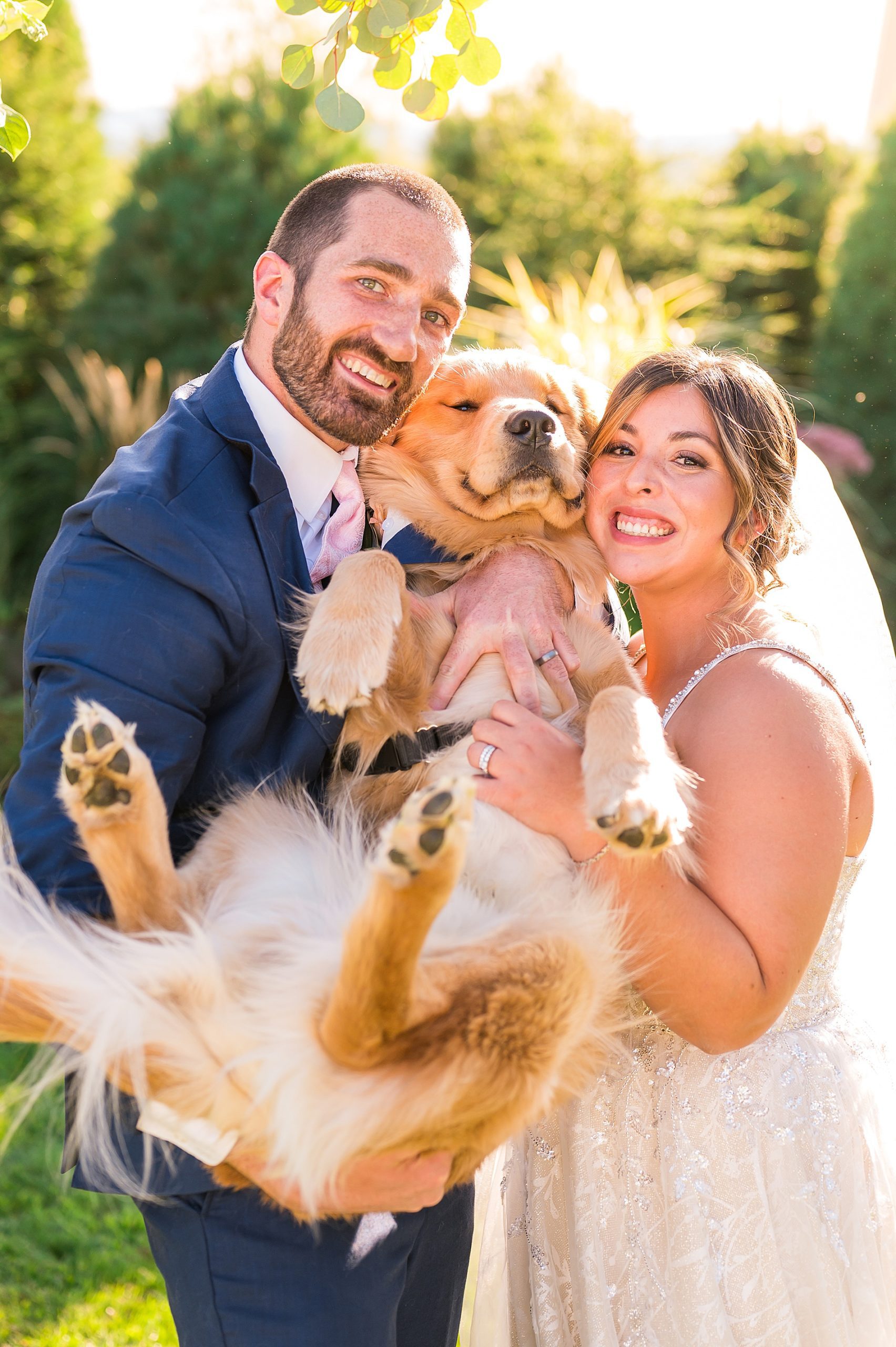 newlyweds hold their dog after wedding ceremony 