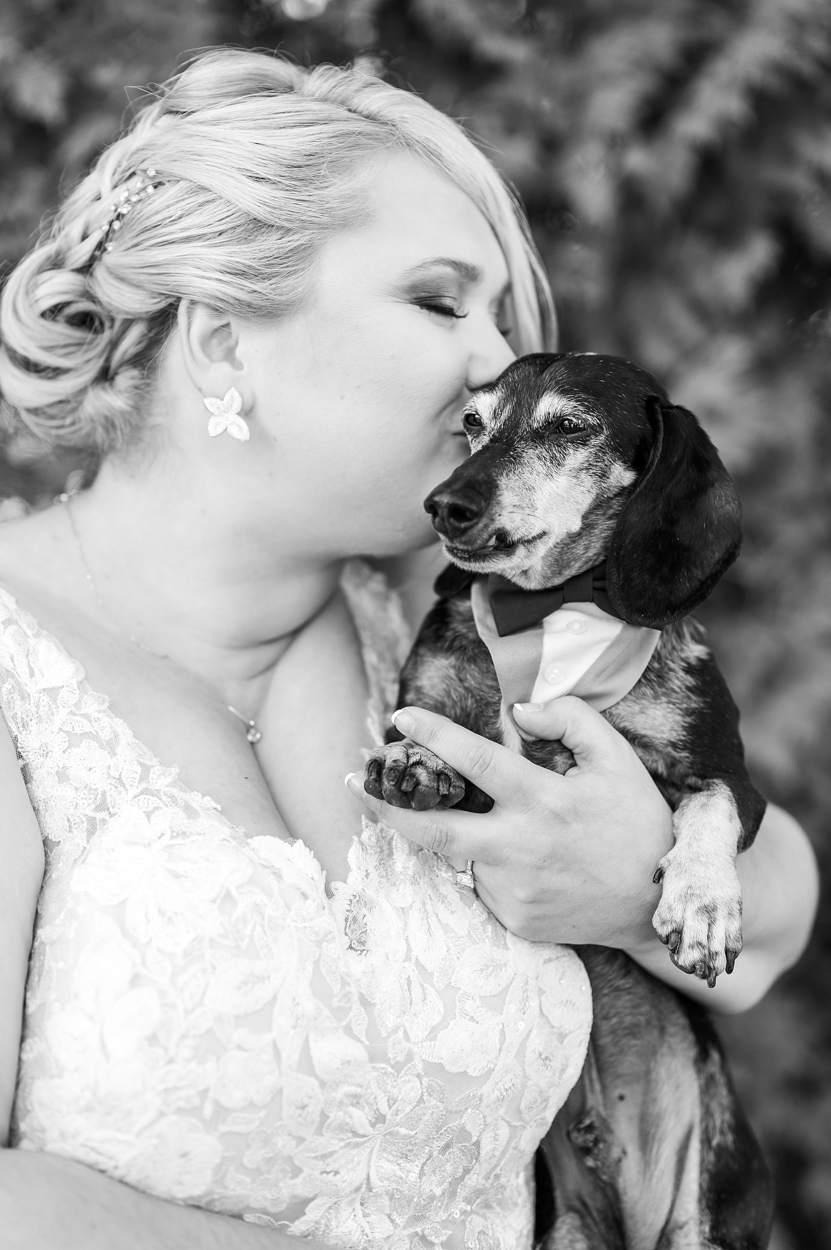 bride holds her small dog and gives him a kiss
