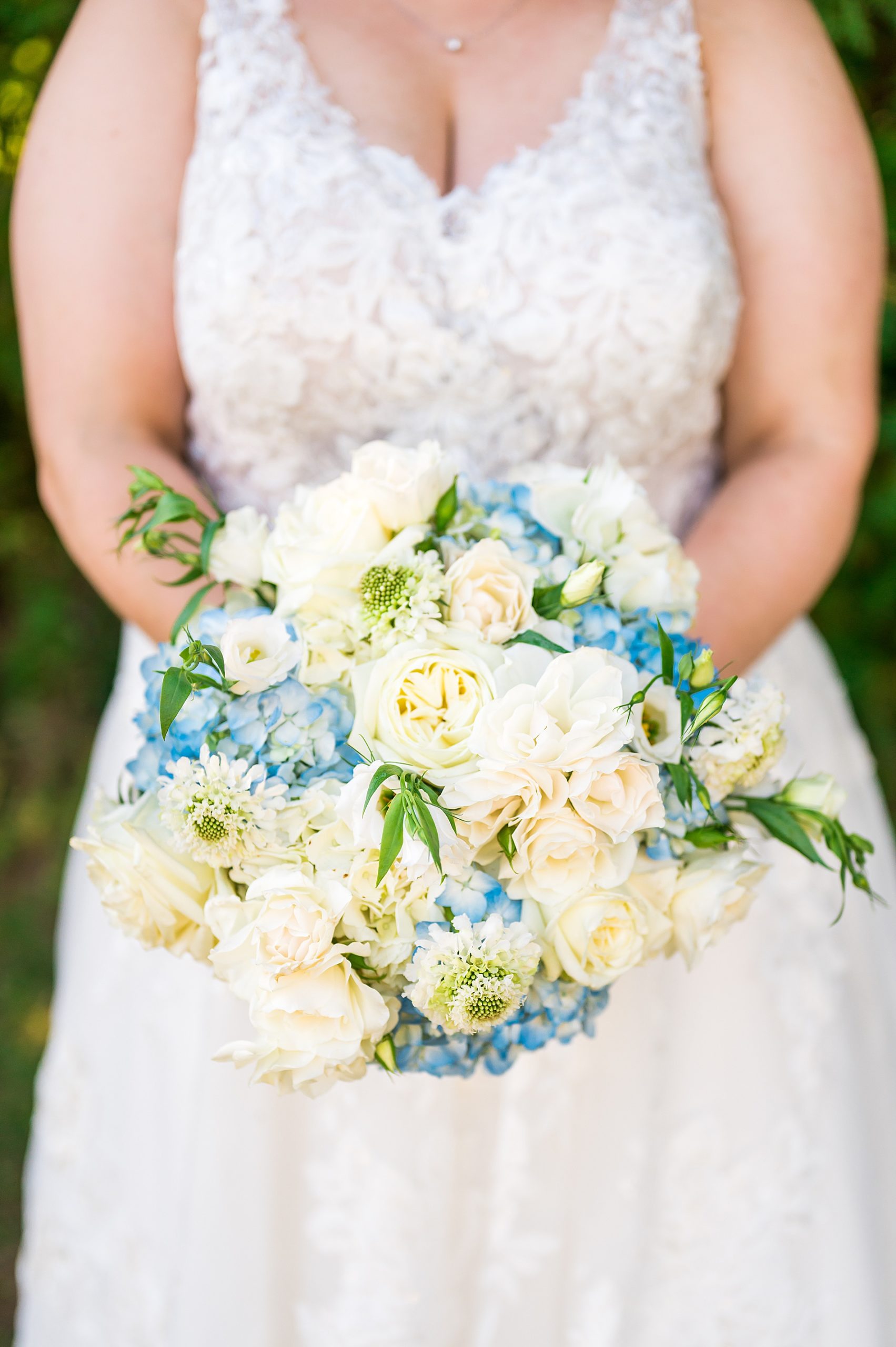 bride holding stunning white and blue flower bouquet