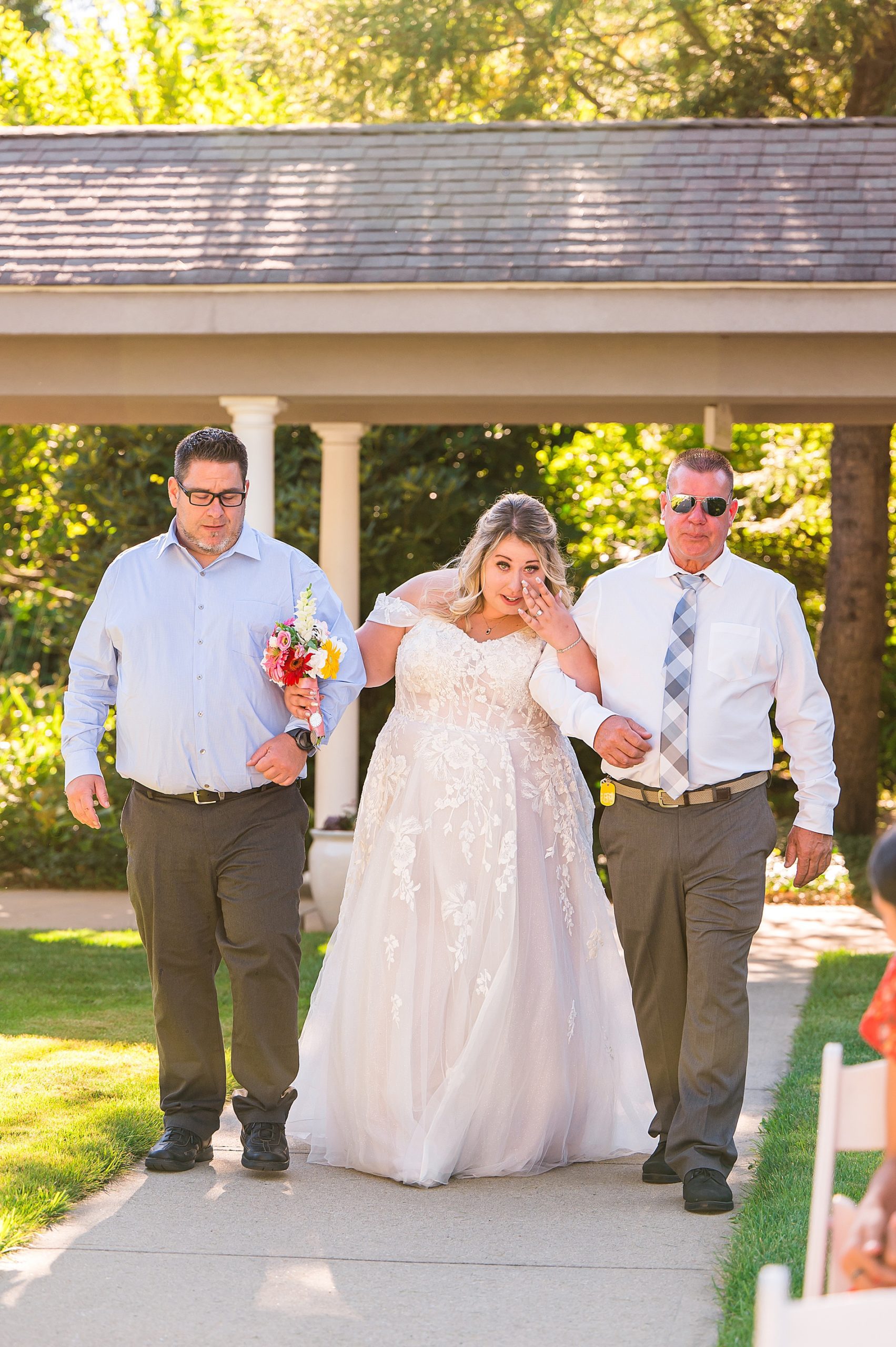 bride walking down the aisle with dad and step-dad