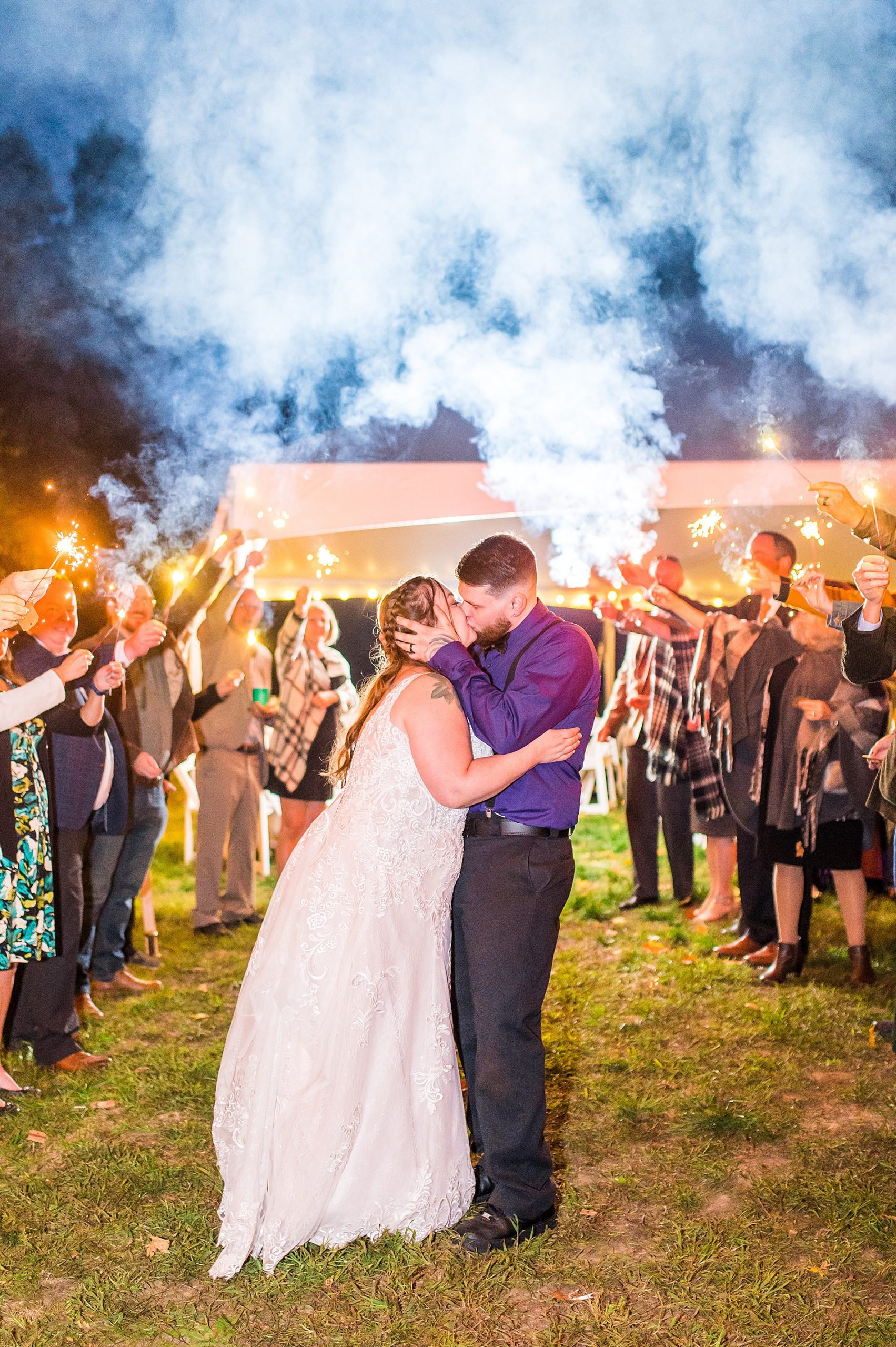 wedding guests hold sparklers as bride and groom exit the reception