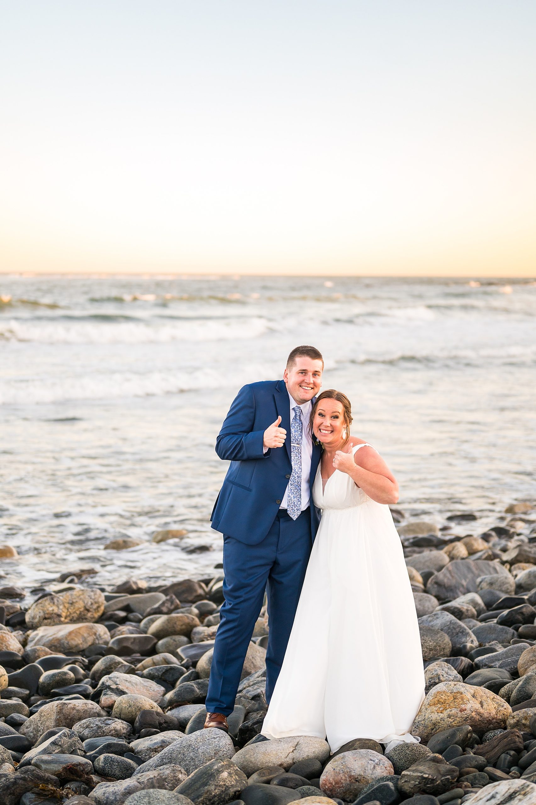 newlyweds give a thumbs up sign during beach wedding portraits 
