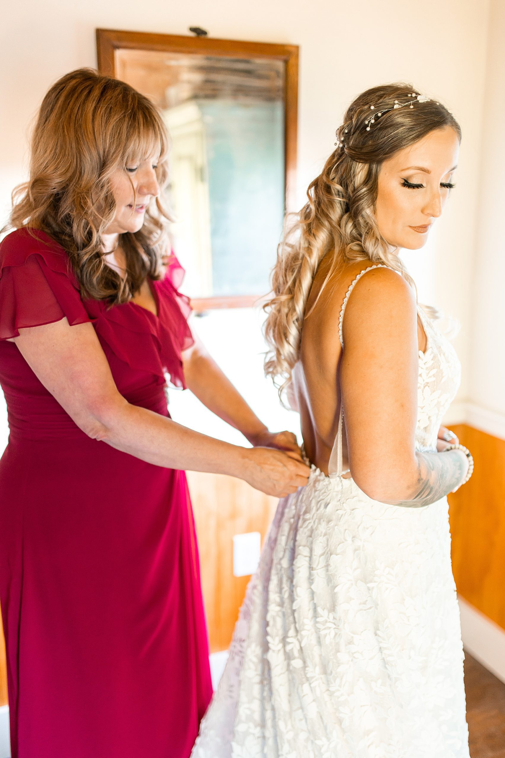 mom of the bride helps her into dress