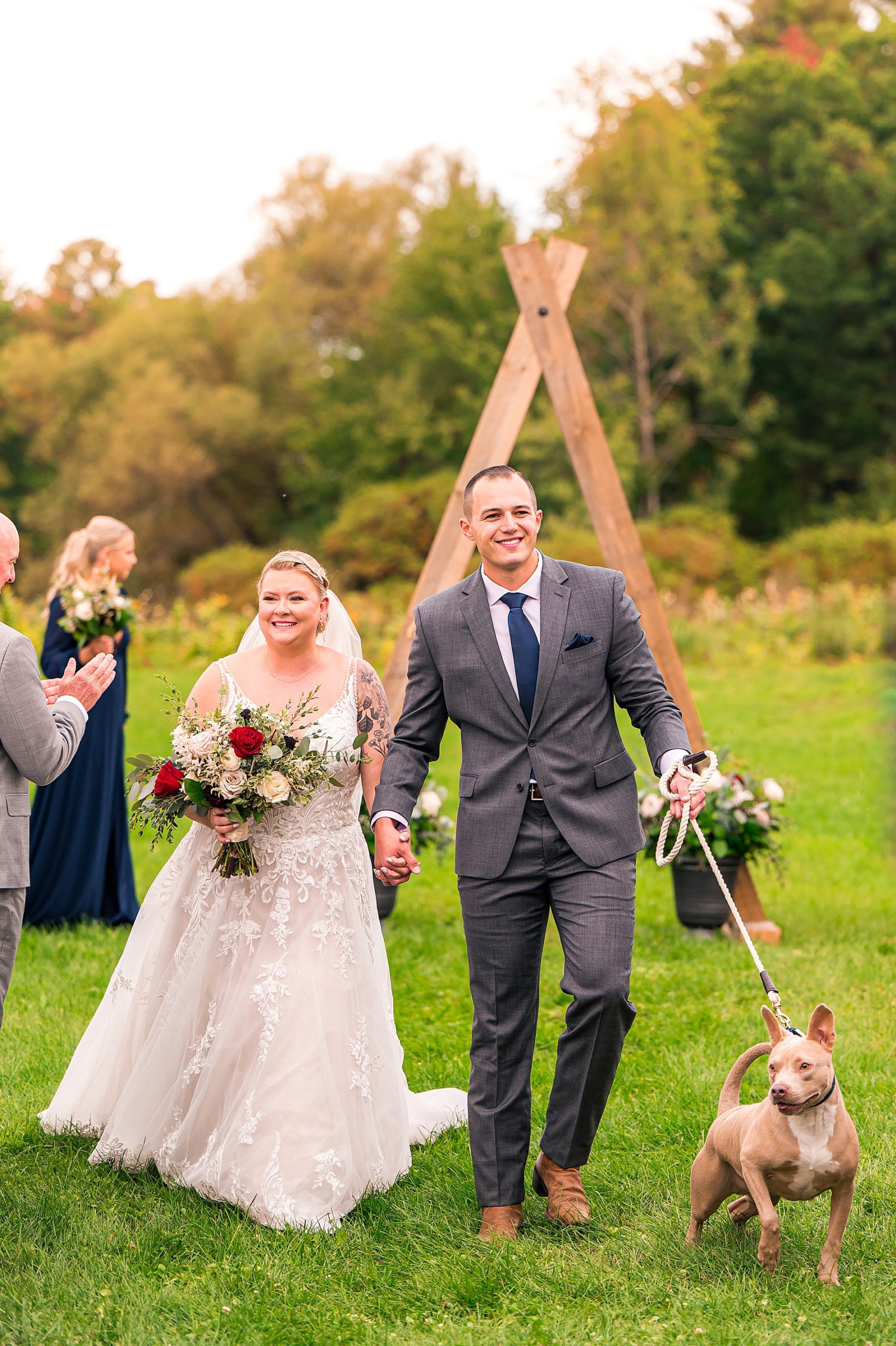 couple walk together after wedding ceremony with their dog 