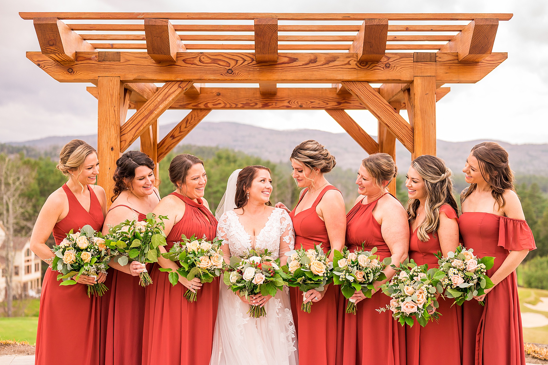 bridesmaids in terracotta dresses stand with bride holding wedding bouquets 