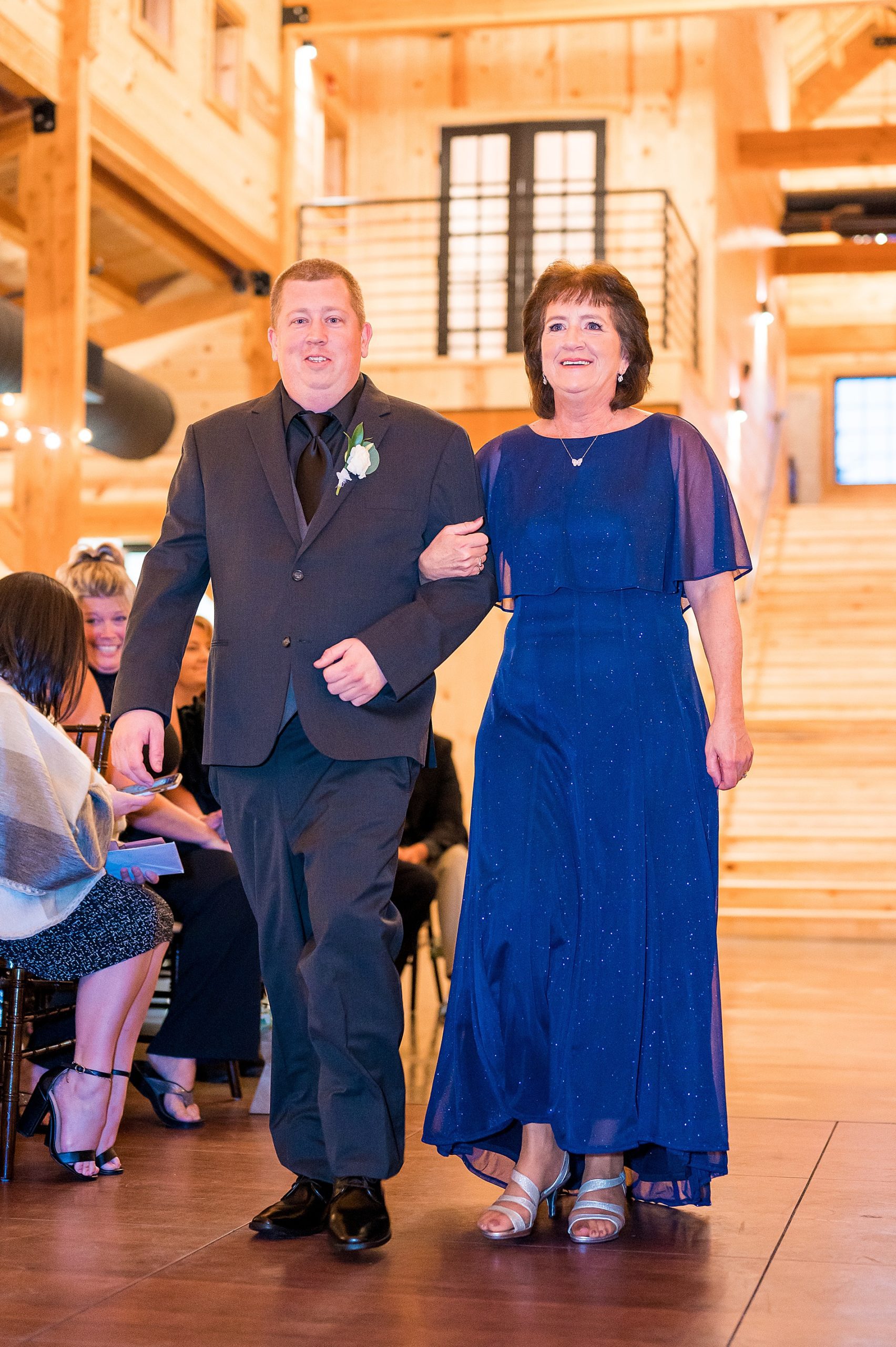 groom walks down the aisle with his mom
