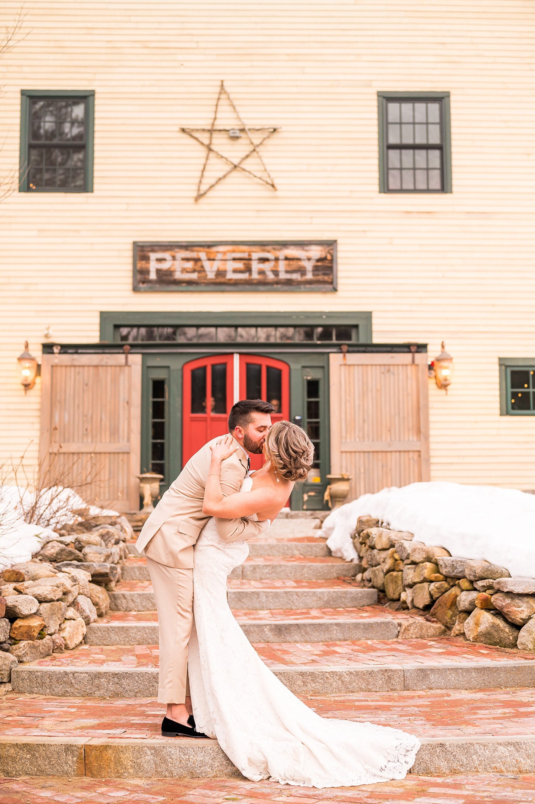 groom kisses his bride on the stairs of barn