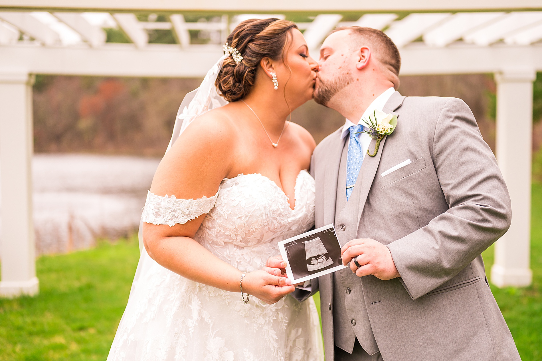 newlyweds hold up ultrasound photo during wedding portraits 
