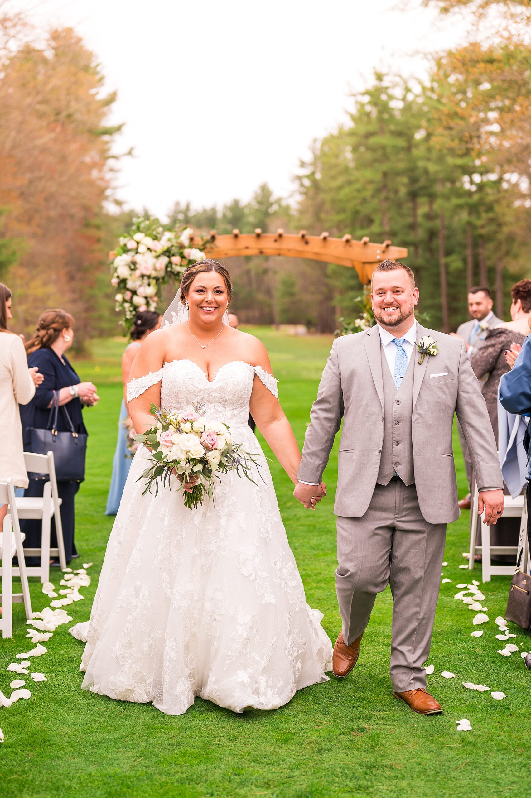 couple hold hands as the exit their Elegant Spring Wedding ceremony at Butternut Farm Golf Club