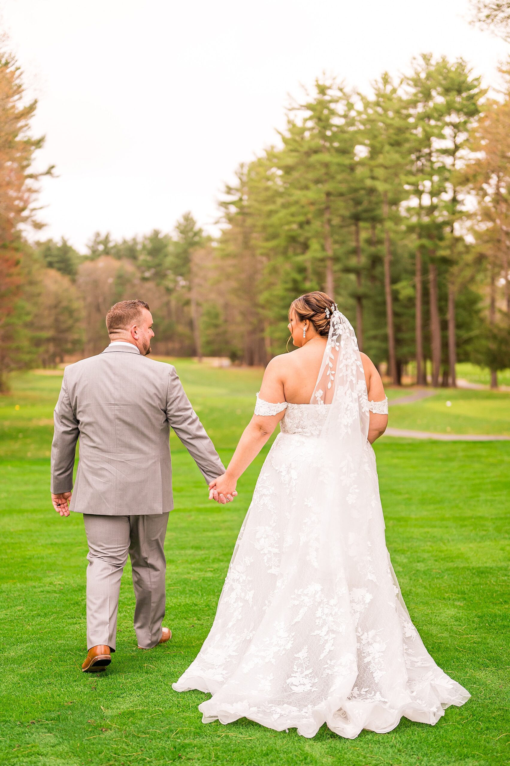 newlyweds hold hands during wedding portraits 