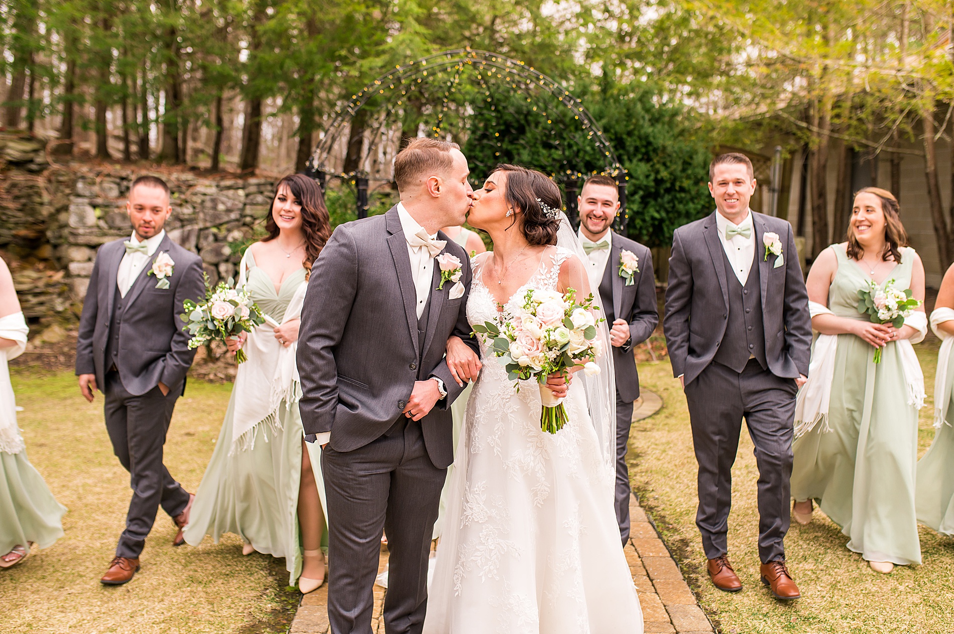 newlyweds kiss as wedding party walks behind them