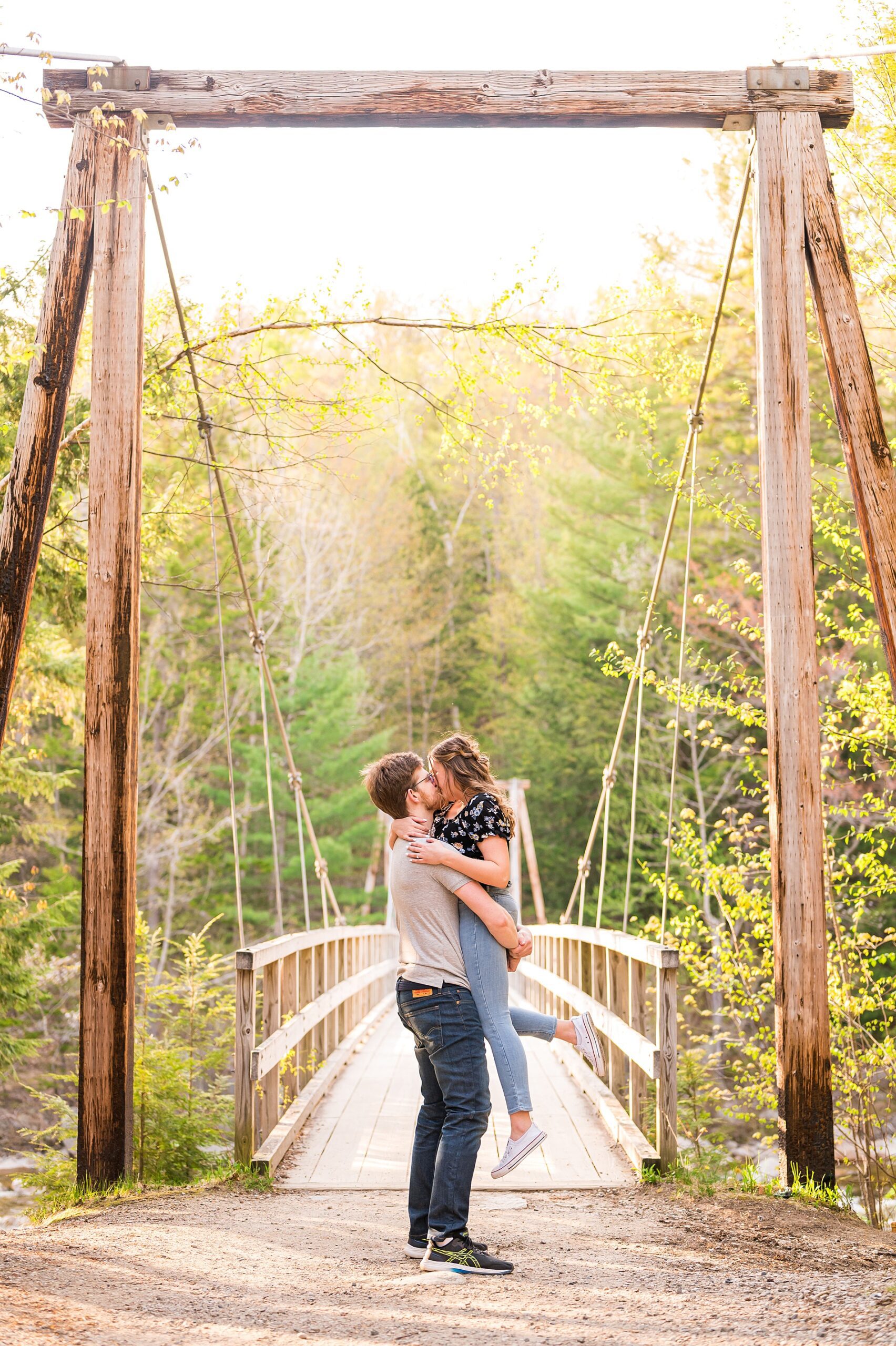 engaged couple kiss in front of bridge in New England
