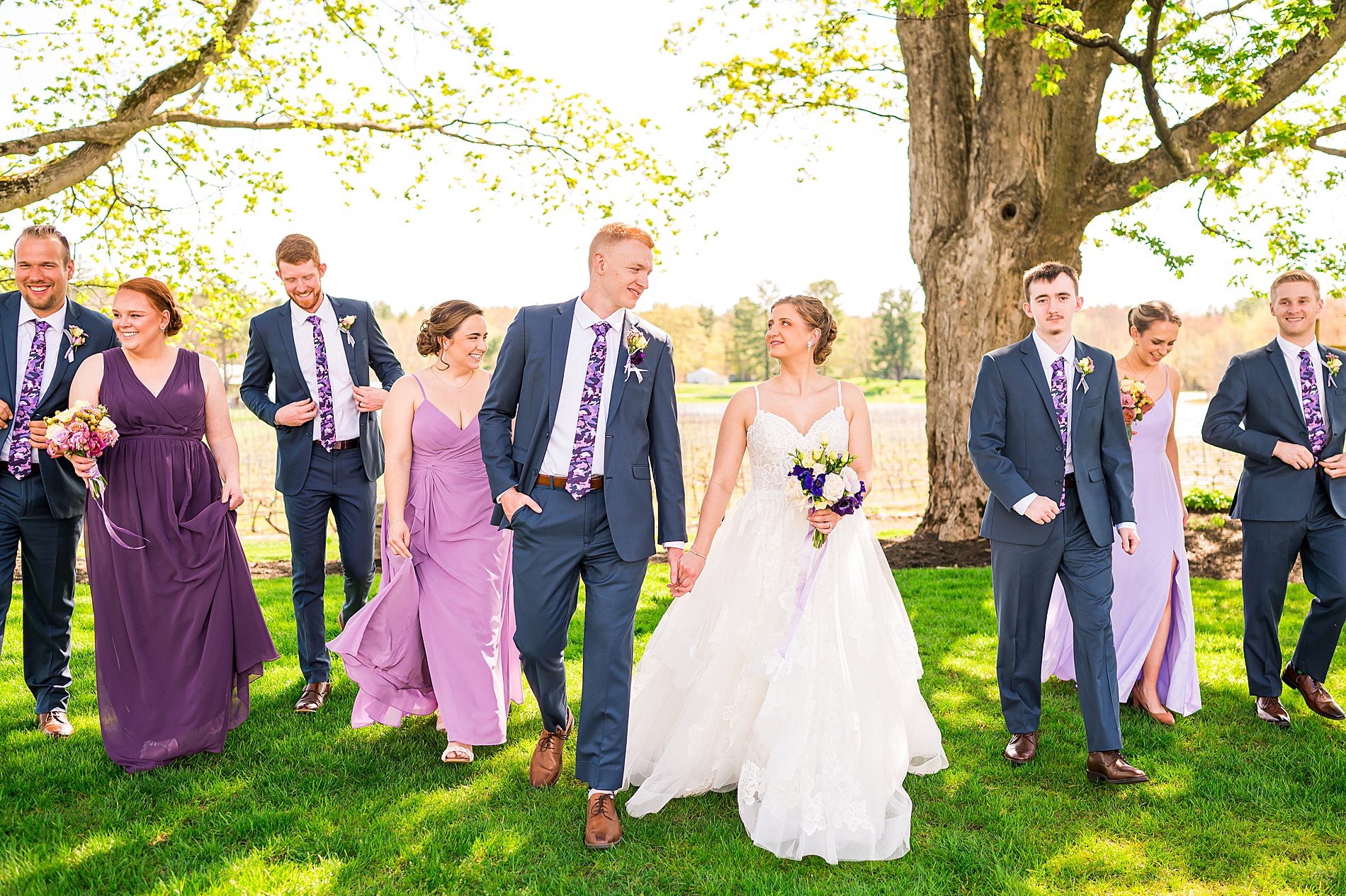bride and groom hold hands as wedding party walks behind them