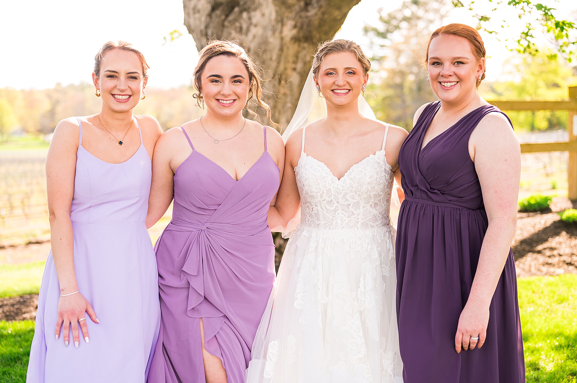 bride with bridesmaids in different purple dresses 