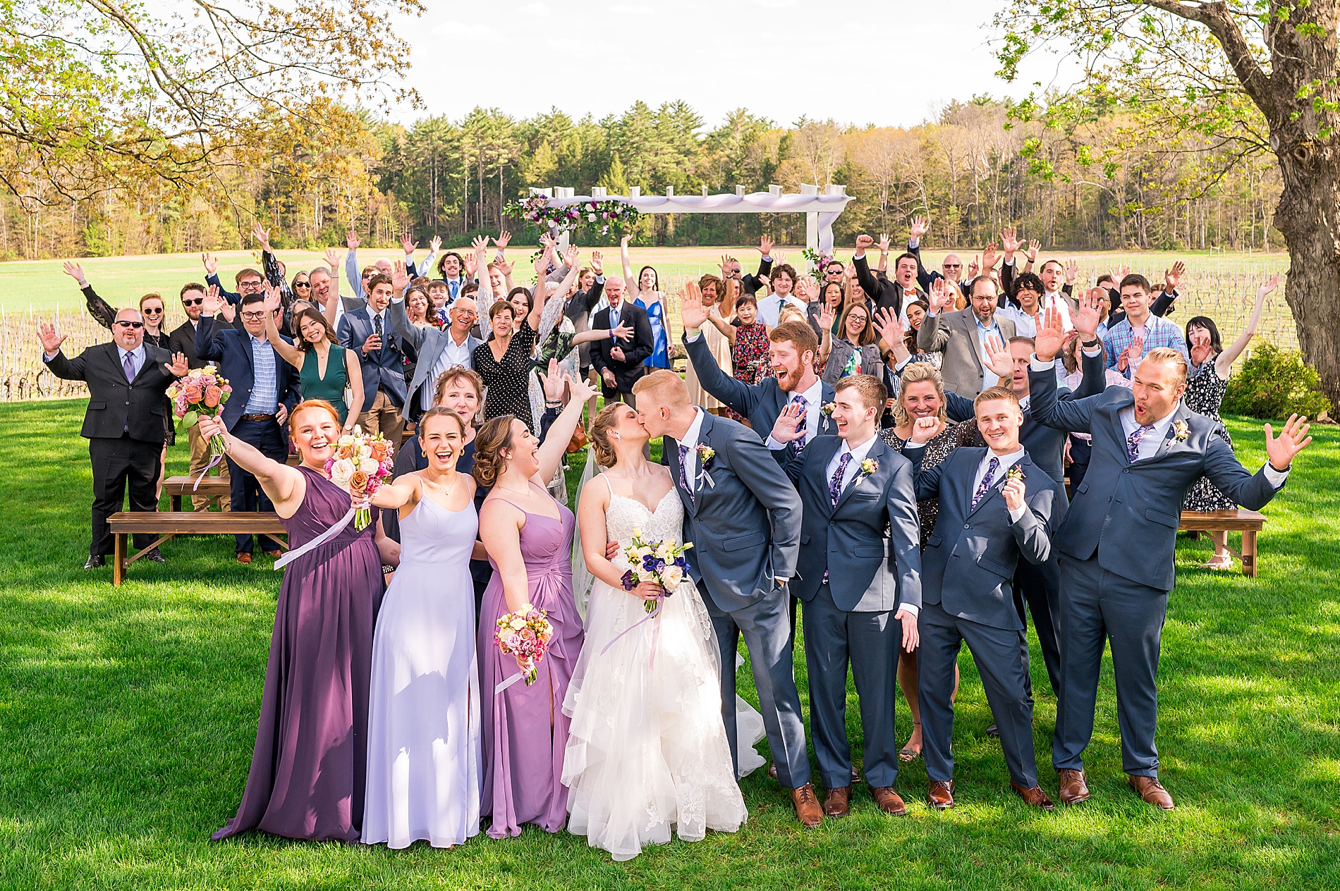 newlyweds kiss with all their wedding guests behind them after Flag Hill Winery Wedding