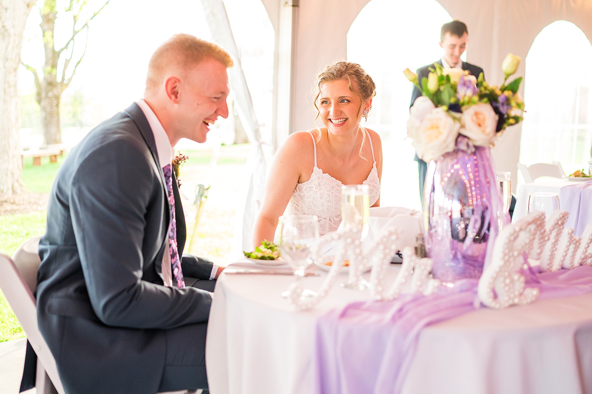 candid photo of newlyweds laughing together at head table