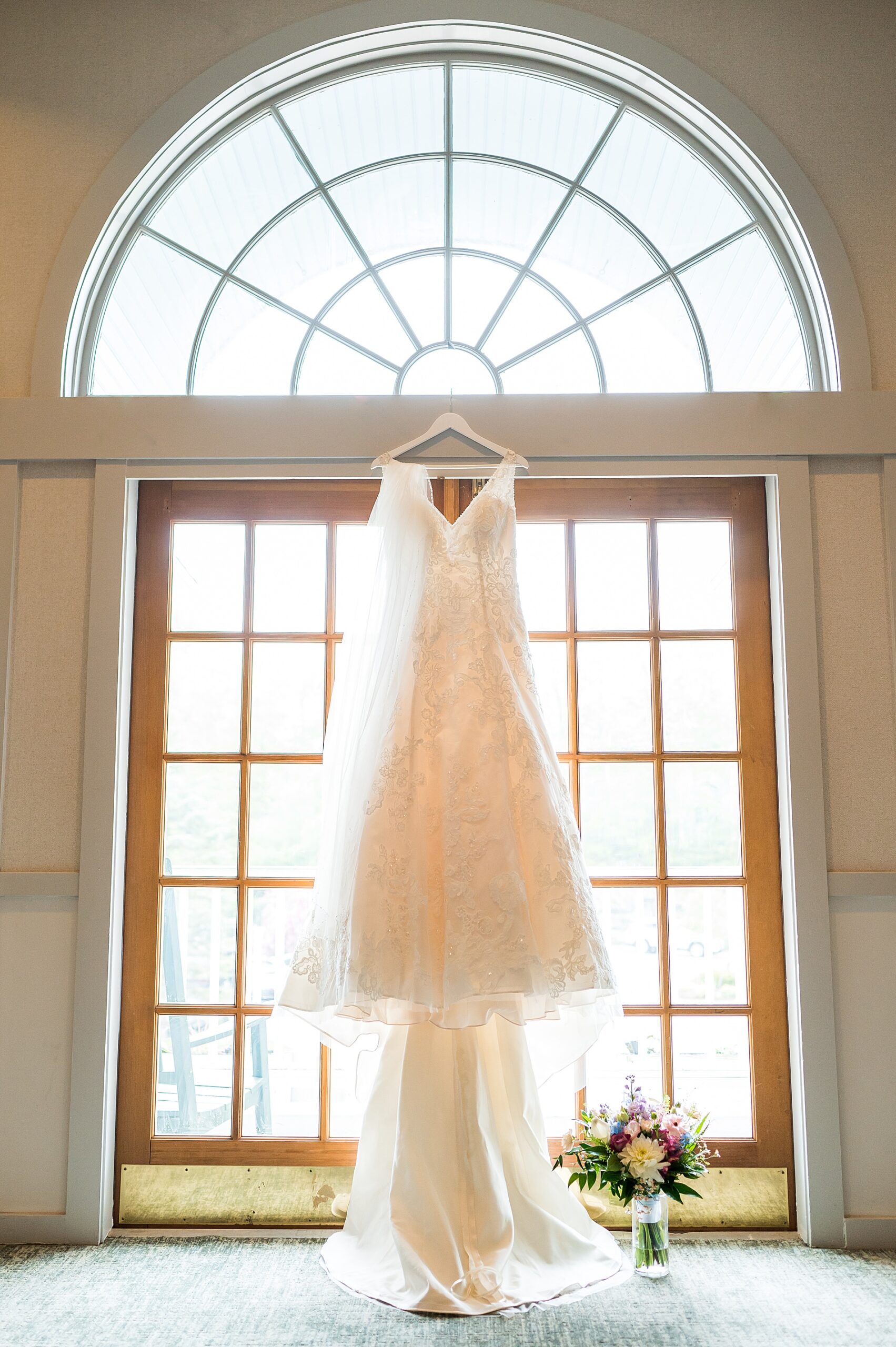 wedding dress hanging from large window 