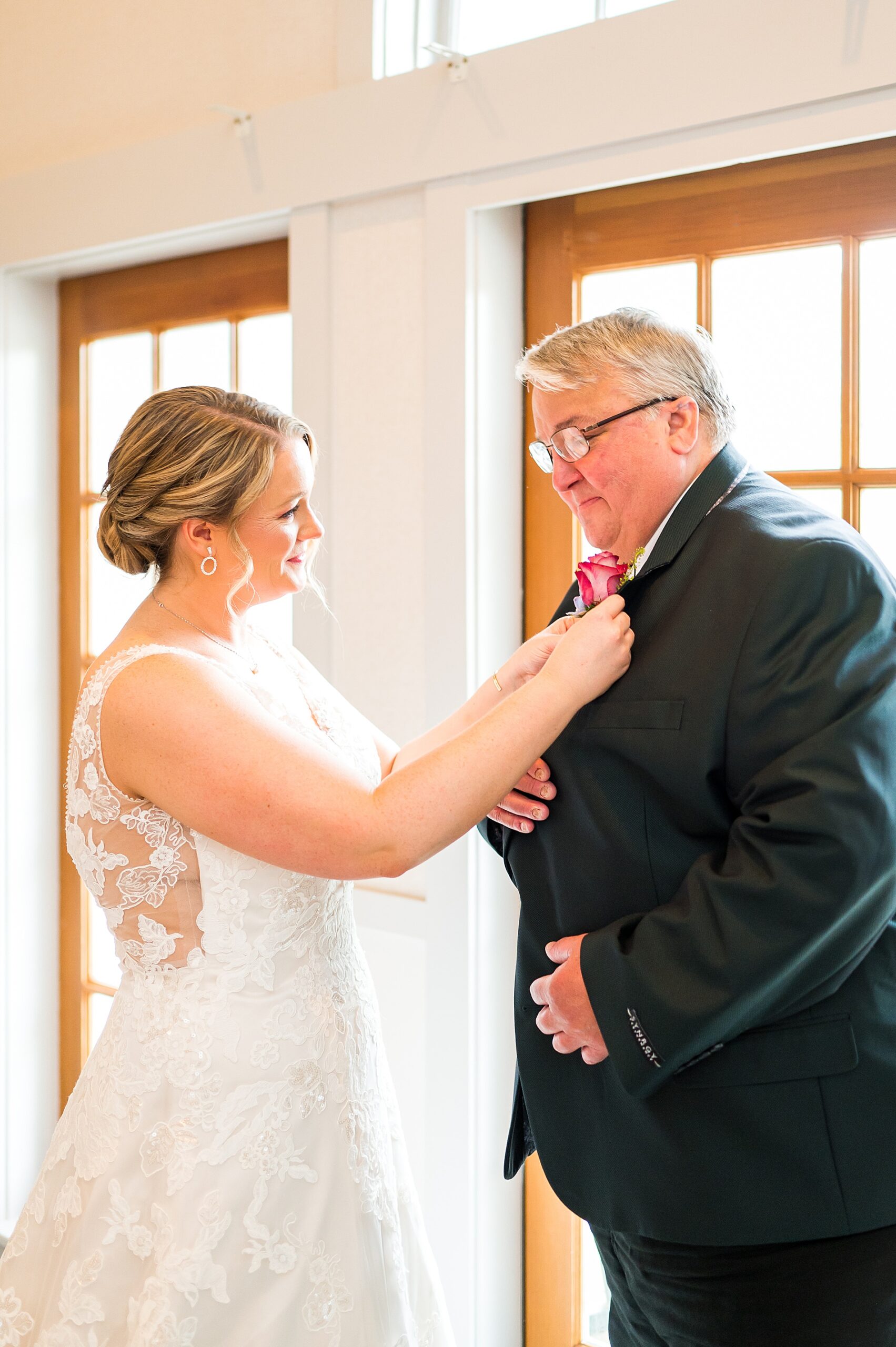 bride pins boutonniere on father's jacket before Spring Wedding at Church Landing