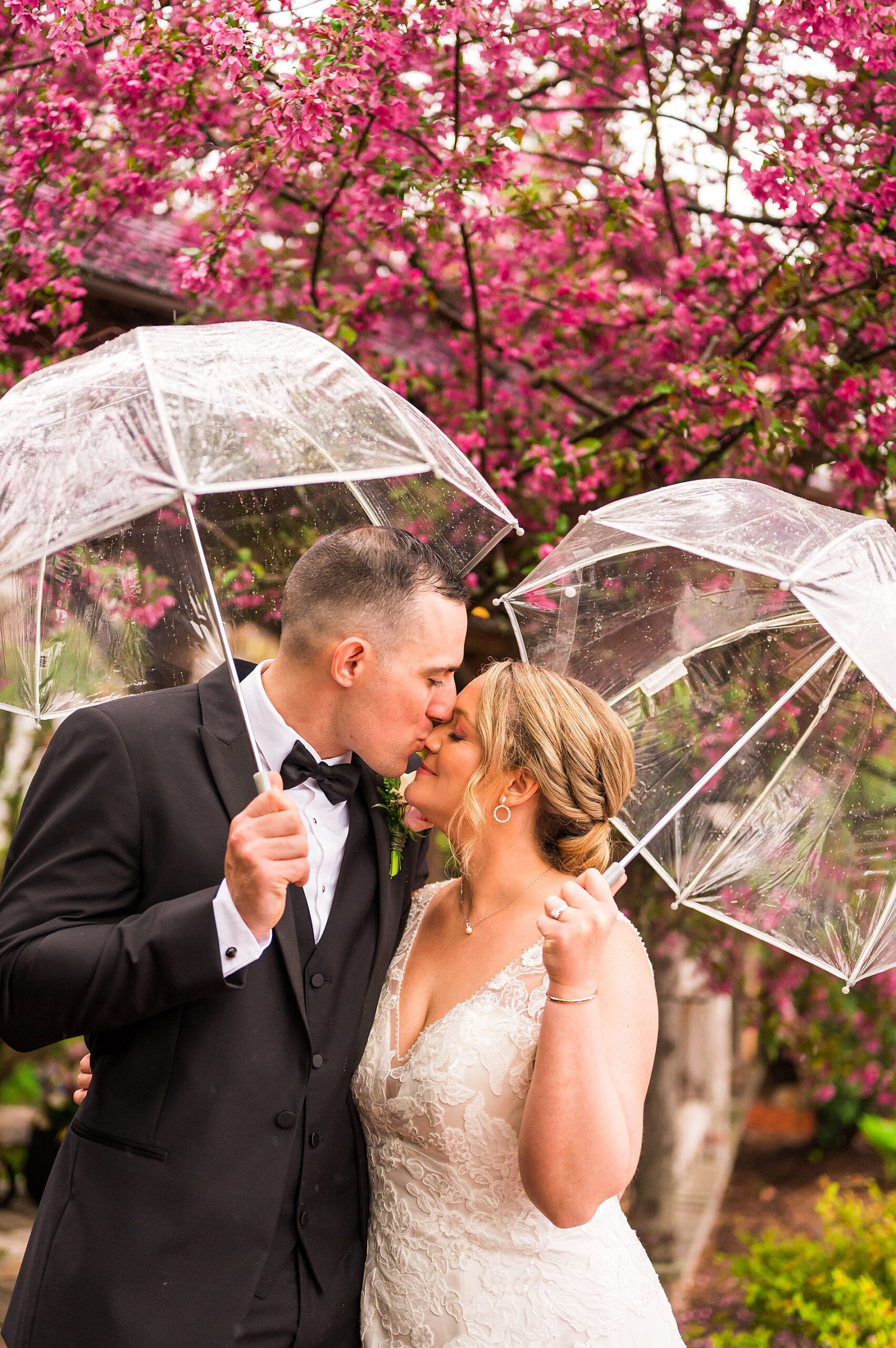 wedding portaits of couple in the rain holding clear umbrellas 