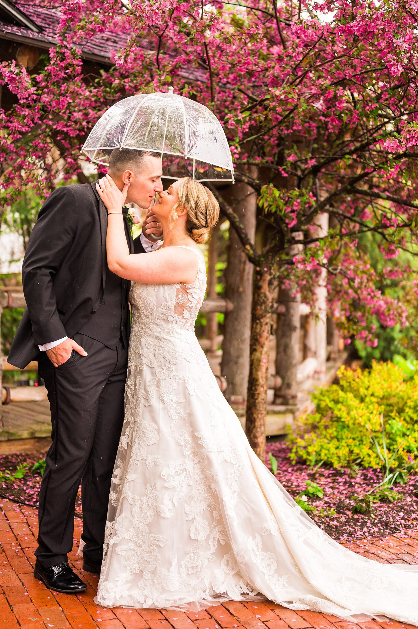 couple kiss under clear umbrella during romantic spring Wedding portraits at Church Landing