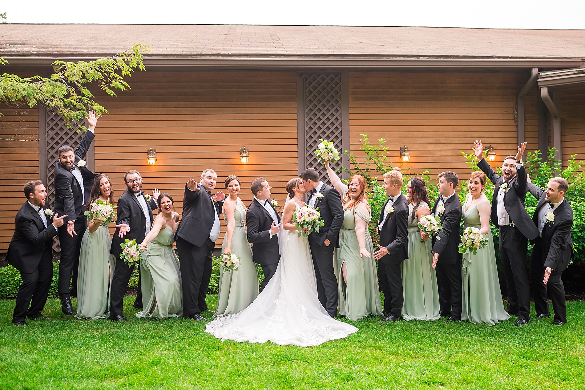 wedding party cheers as newlyweds kiss