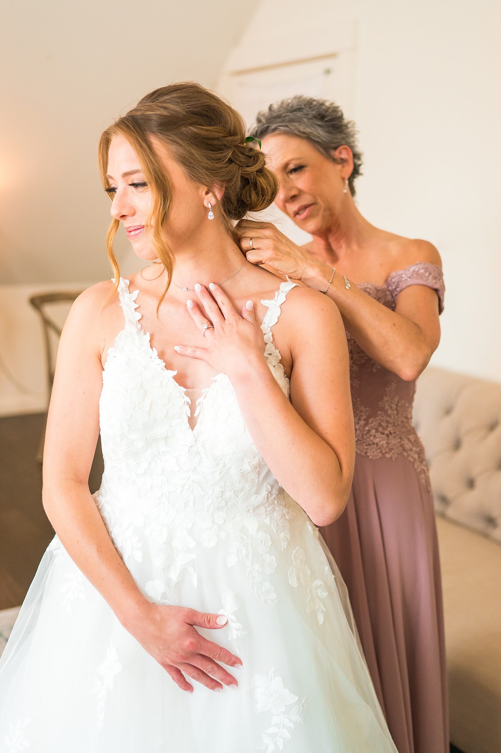bride getting help from her mom getting ready