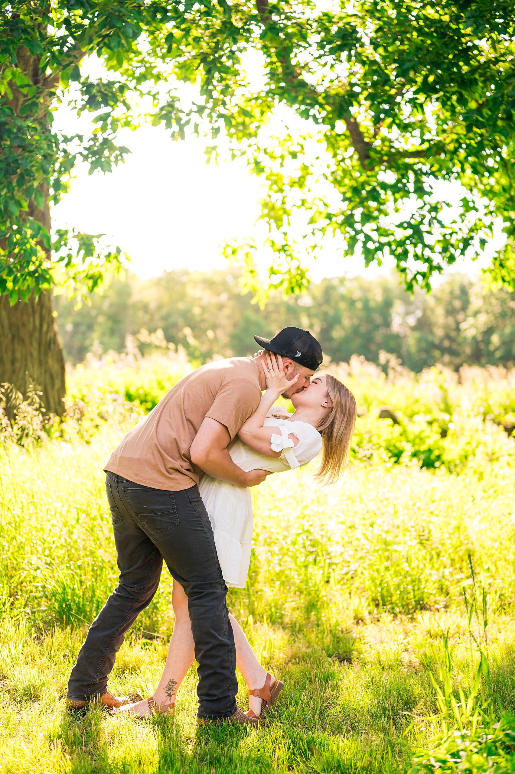 engaged couple kiss in field of tall grass