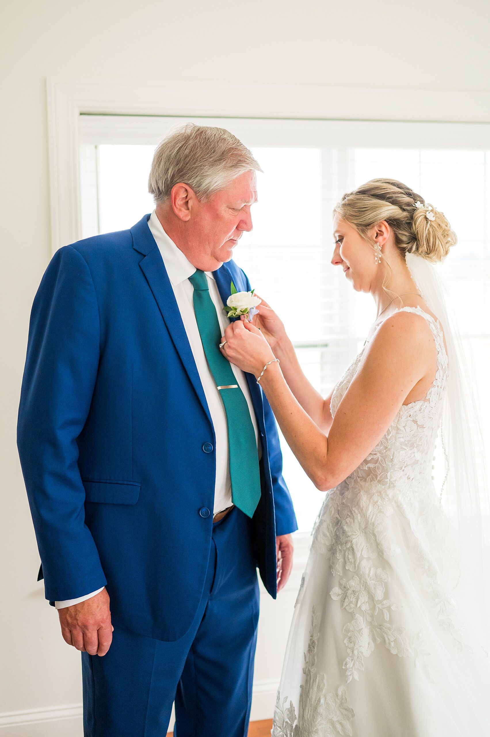 bride pins boutonniere on her dad's suit