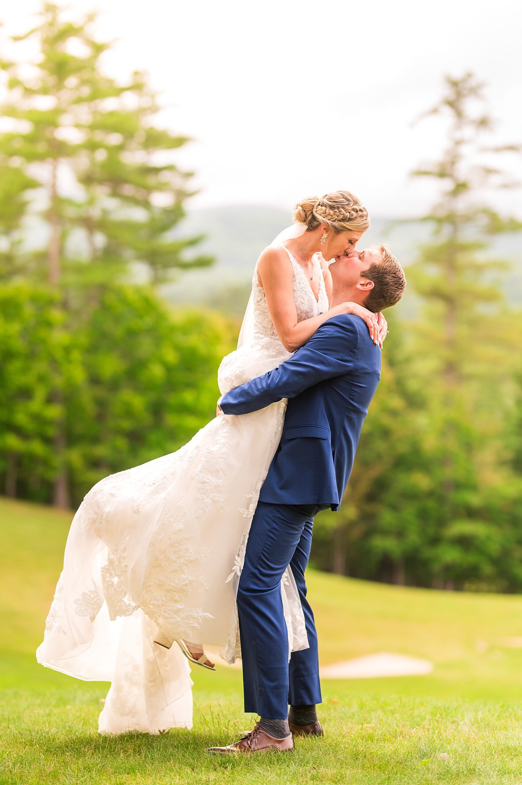 groom lifts his bride as they kiss during wedding portraits