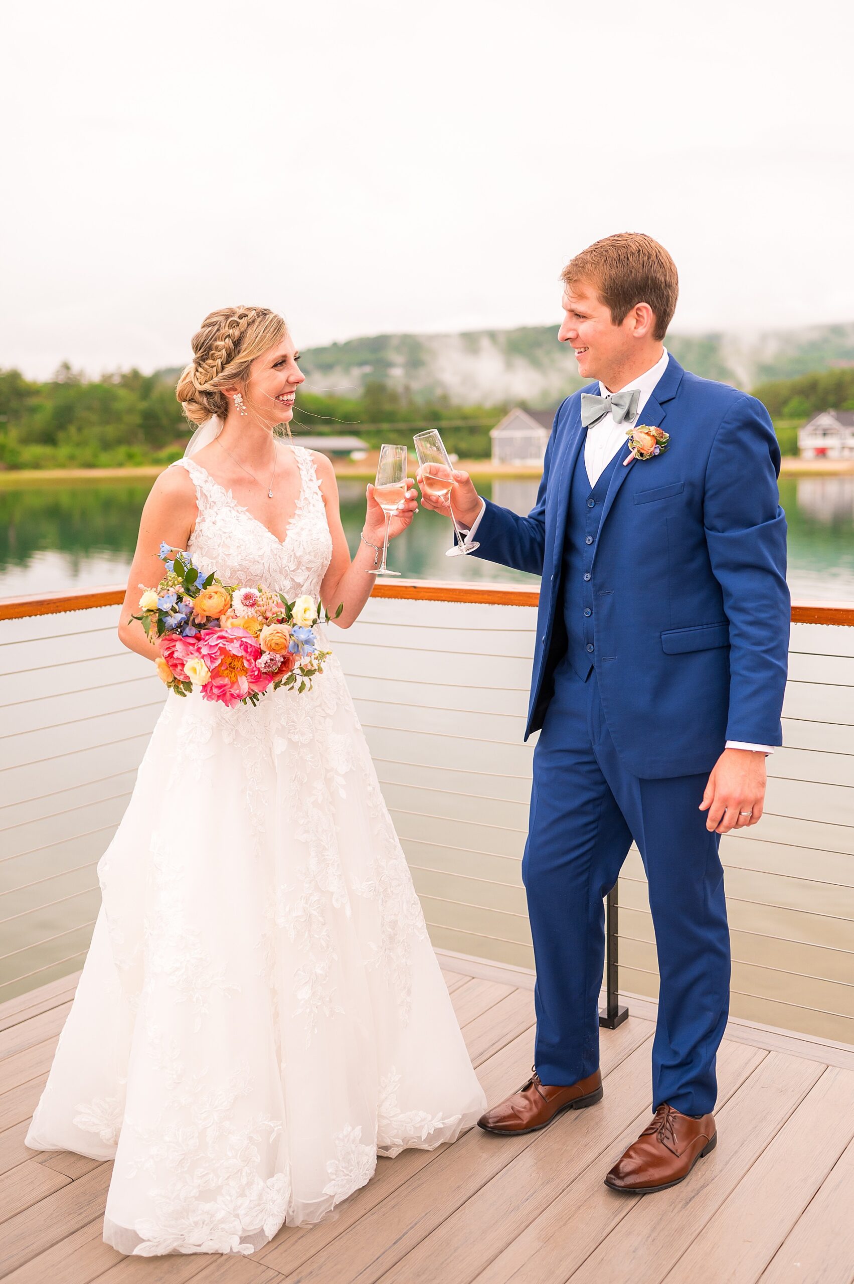  newlyweds toast on balcony overlooking the water from Summer Wedding at Owl's Nest Resort  