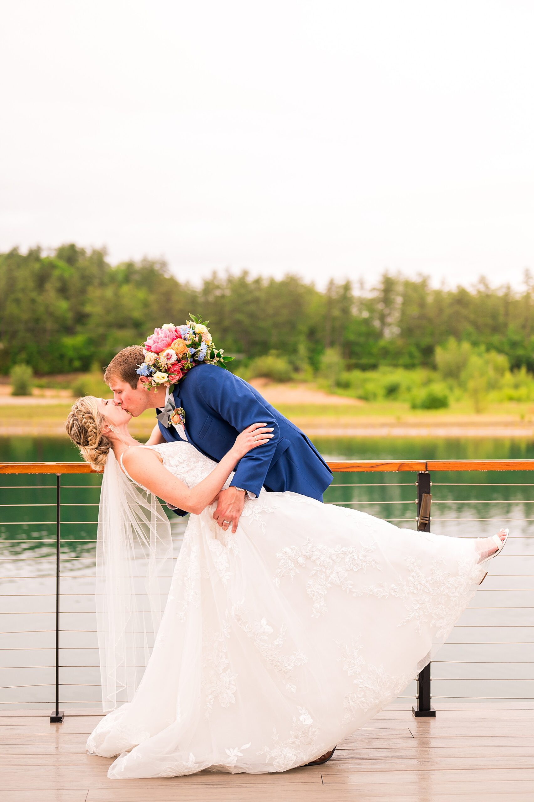newlyweds kiss on balcony of Lakehouse at Owl's Nest Resort  