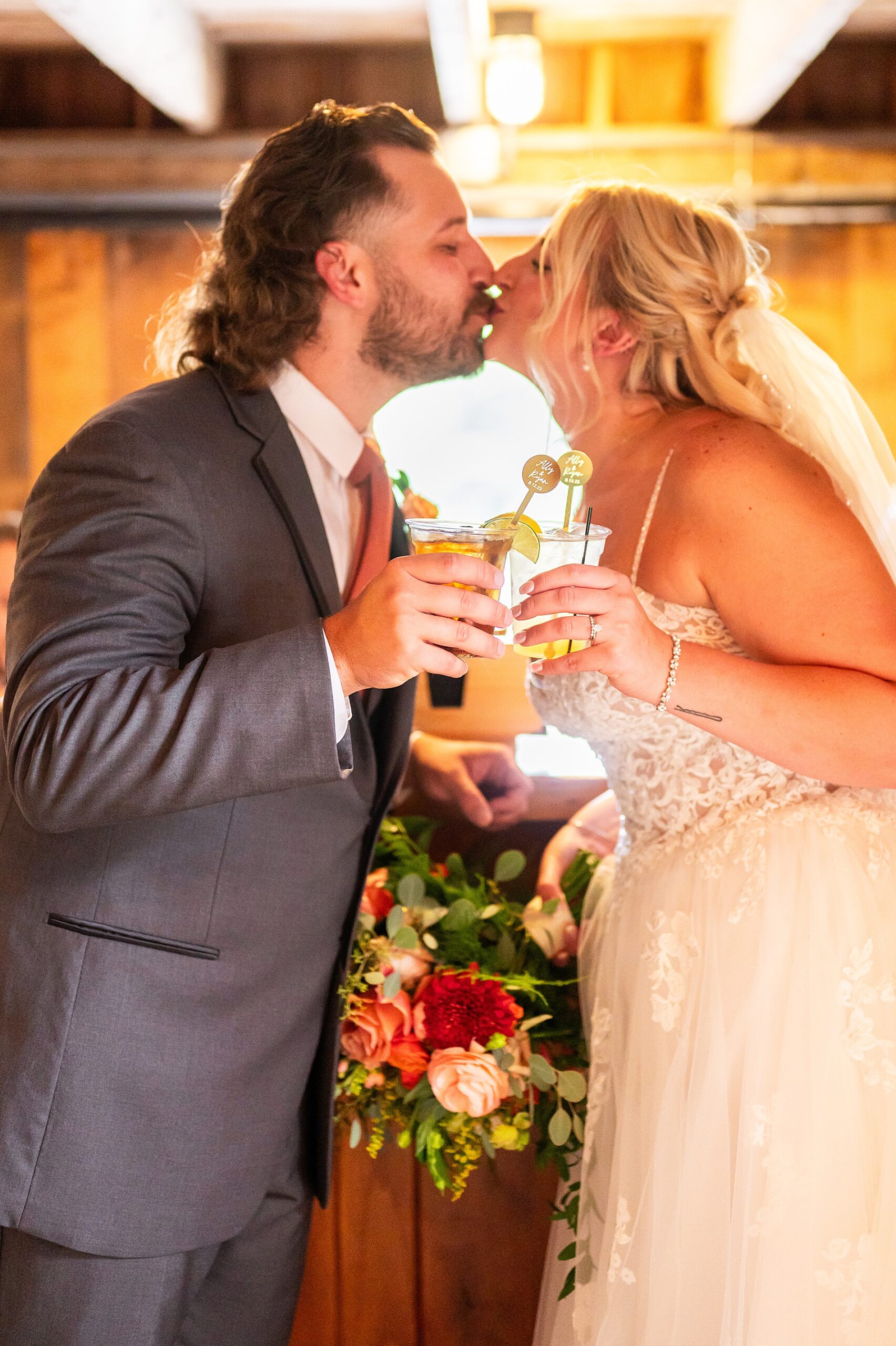 newlyweds kiss holding their signature drinks